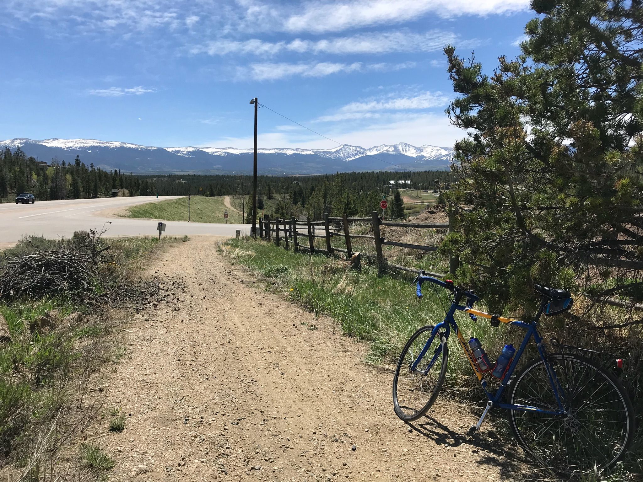 A bicycle parked on a dirt path with a fence and snowy mountains beyond. - Fraser – Fraser River Trail loop from Snow Mountain Ranch - YMCA - Northbound