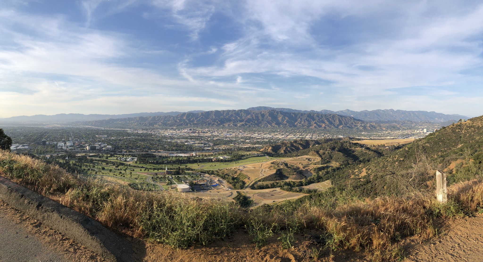 Panoramic view of a wide valley with a city and mountains under cloudy sky. - Back of Hollywood Sign via Hollywood Revisor