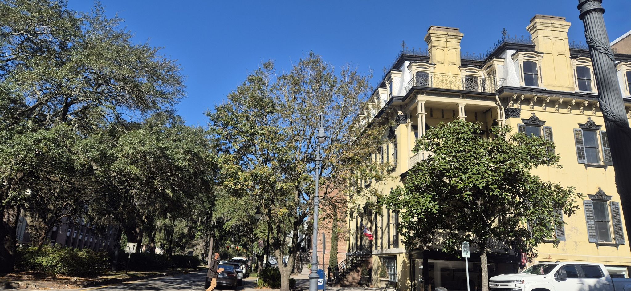A grand yellow building stands beside a tree-lined street on a sunny day. - Monterey Square – Chippewa Square loop from Savannah