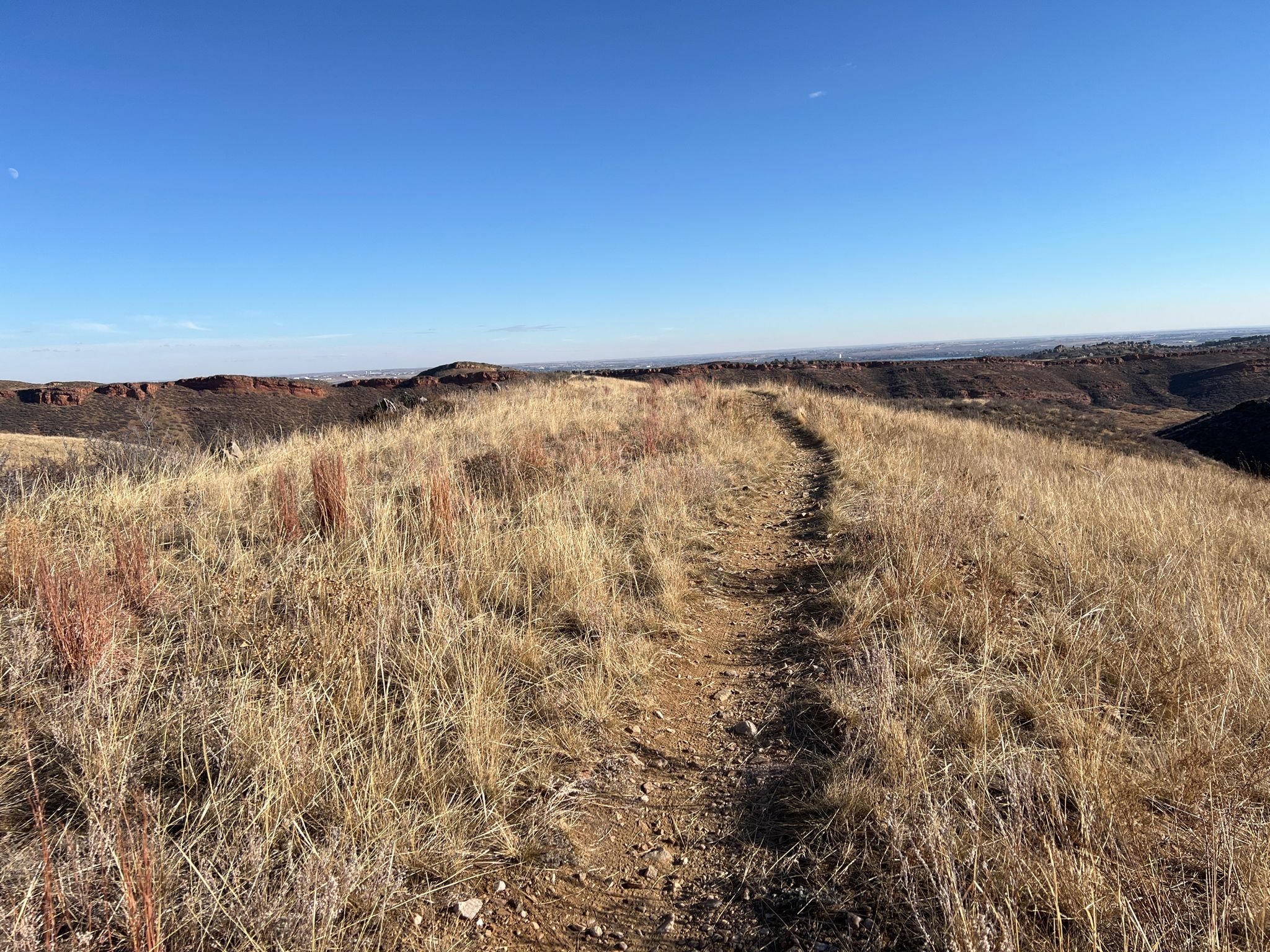 Narrow dirt path through golden dry grass on a hilltop under blue sky. - Blue Sky and Indian Summer Loop