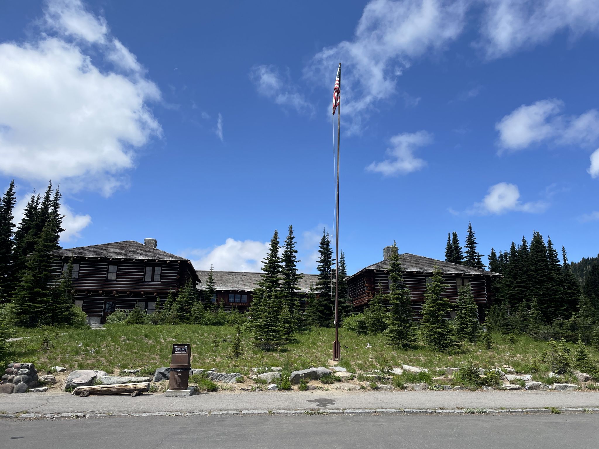 Two rustic wooden lodge buildings and a flagpole under a blue sky. - Sunrise Park Road
