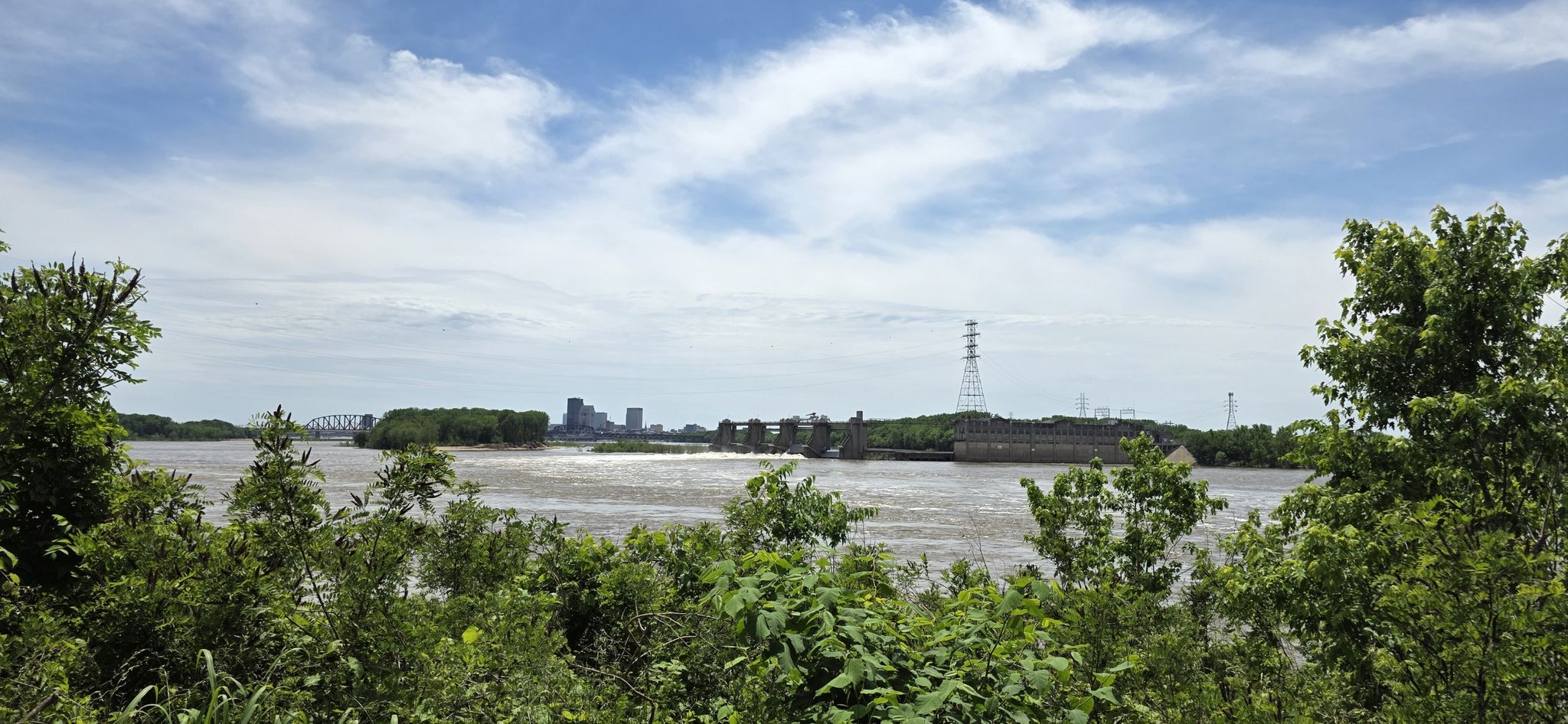Wide river view with distant city and industrial structures under a cloudy sky. - Big Four Bridge – Big Four Station Park loop from Jeffersonville