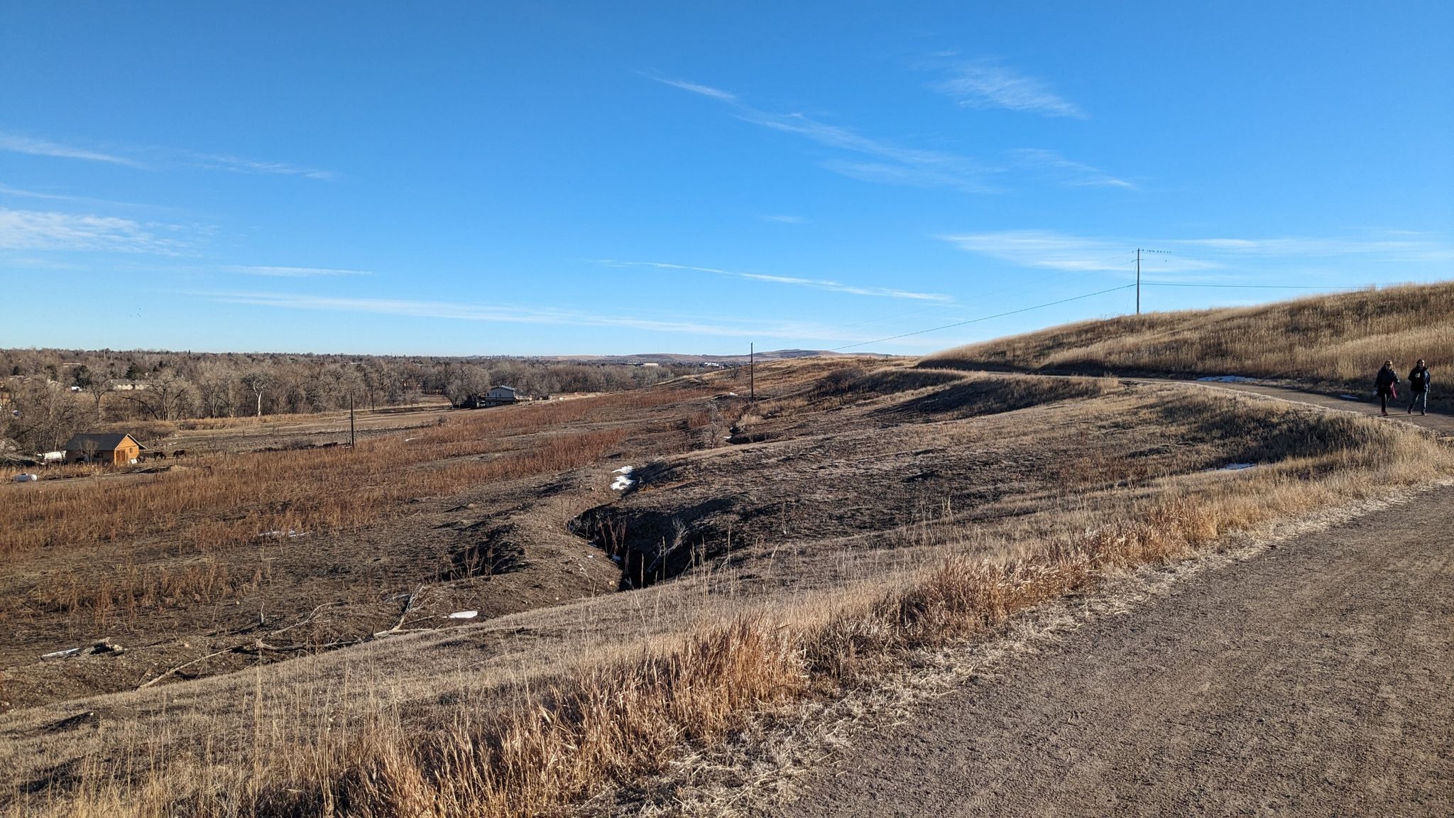 Two people walk on a winding dirt path through dry, brown winter landscape. - Coal Creek and Rock Creek Trail Loop