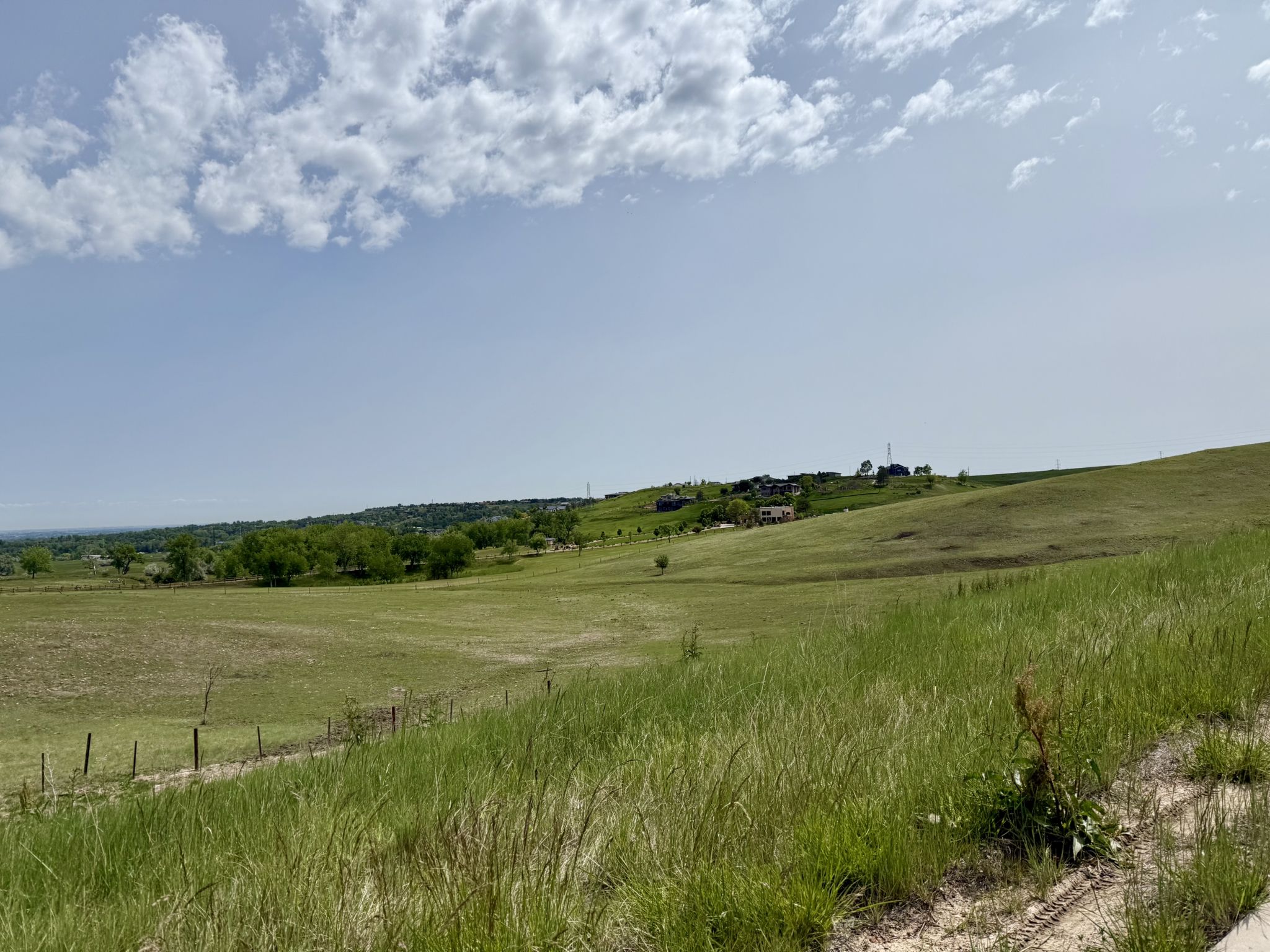 Rolling green hills under a partly cloudy sky with distant houses. - US 36 Bikeway