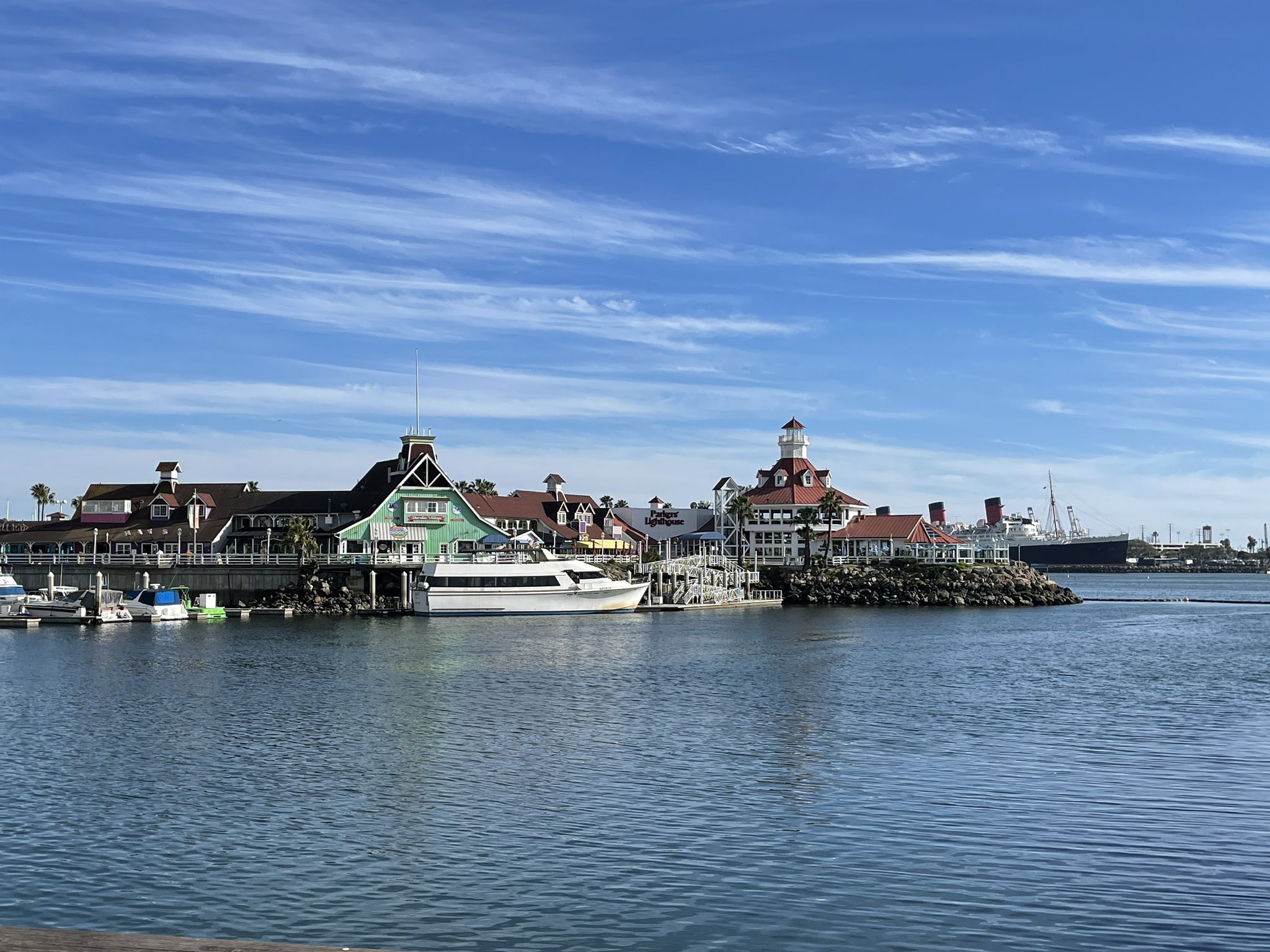 Waterfront with colorful buildings, docked boats, and calm water under a blue sky. - Long Beach Shoreline Loop