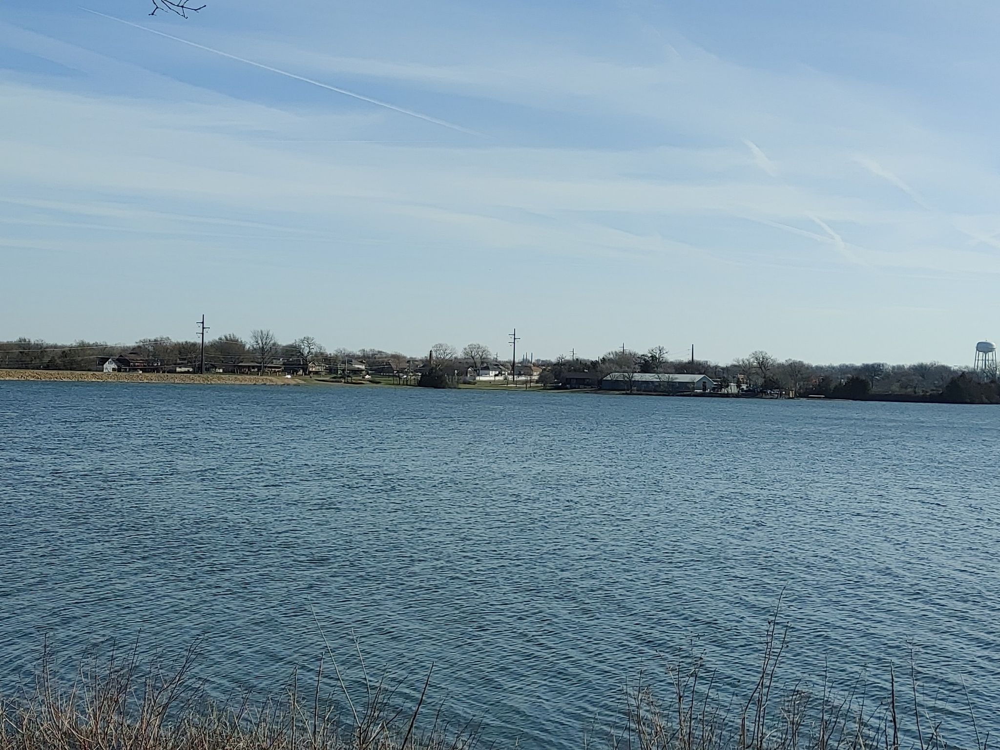 Wide view of a calm lake under a bright blue sky. - Lake Shawnee Trail