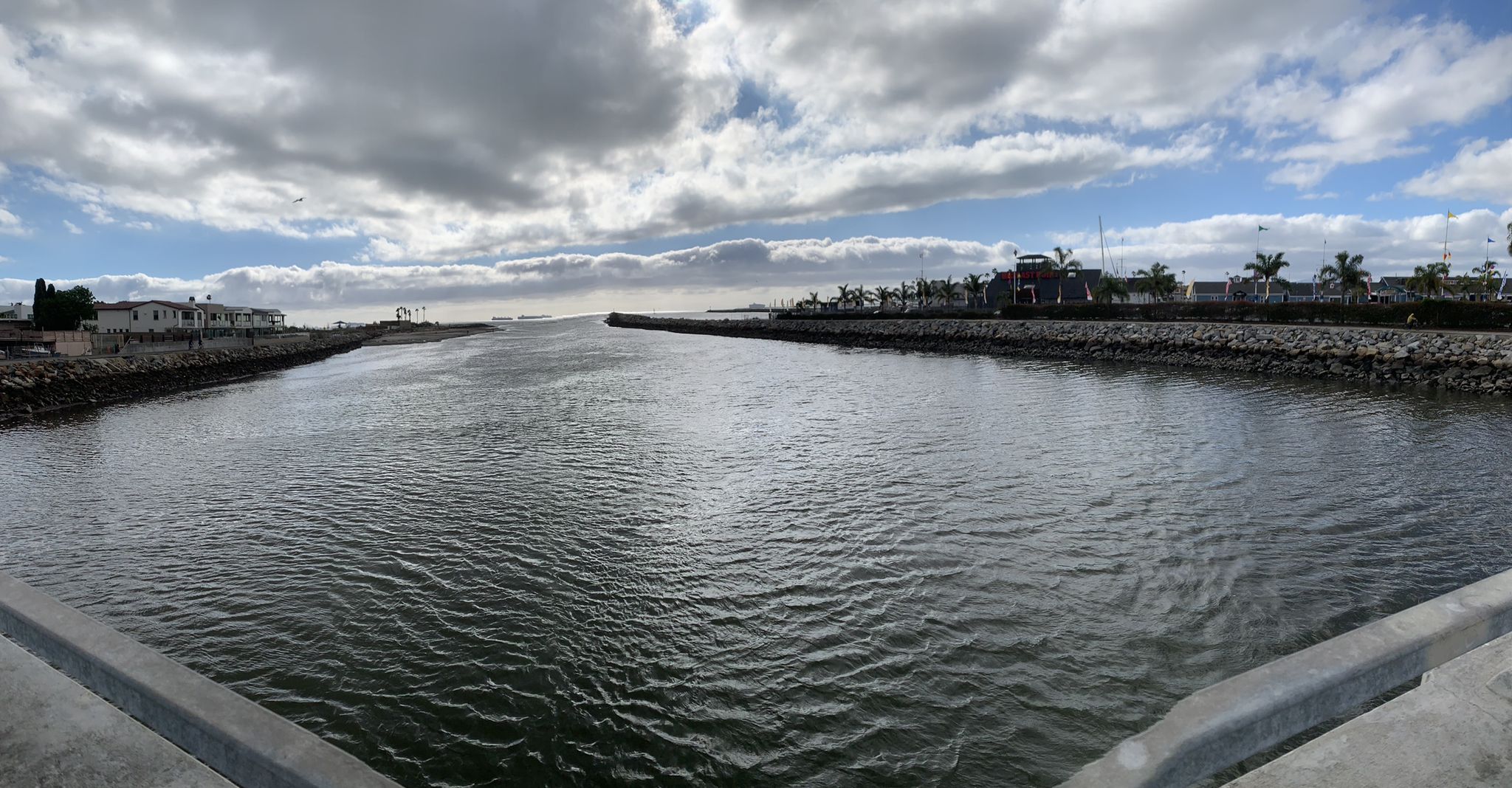 Wide river flowing between rocky banks under a dramatic cloudy sky. - Seal Beach and Pier – Seal Beach loop from Seal Beach