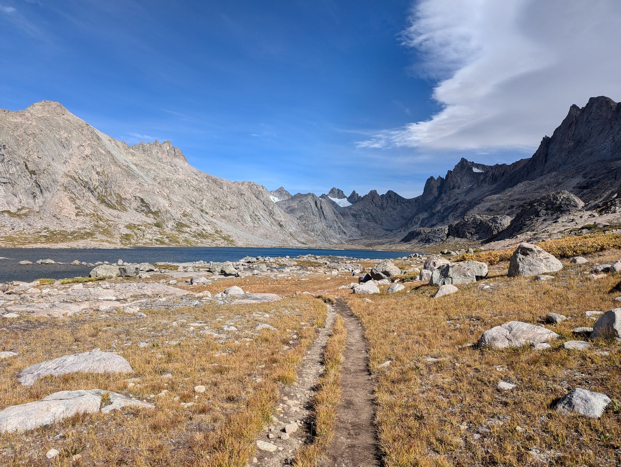 Dirt path leading to a lake surrounded by rugged mountains, partly cloudy. - Titcomb Basin via Pole Creek Trail and Crooks Lakes Loop