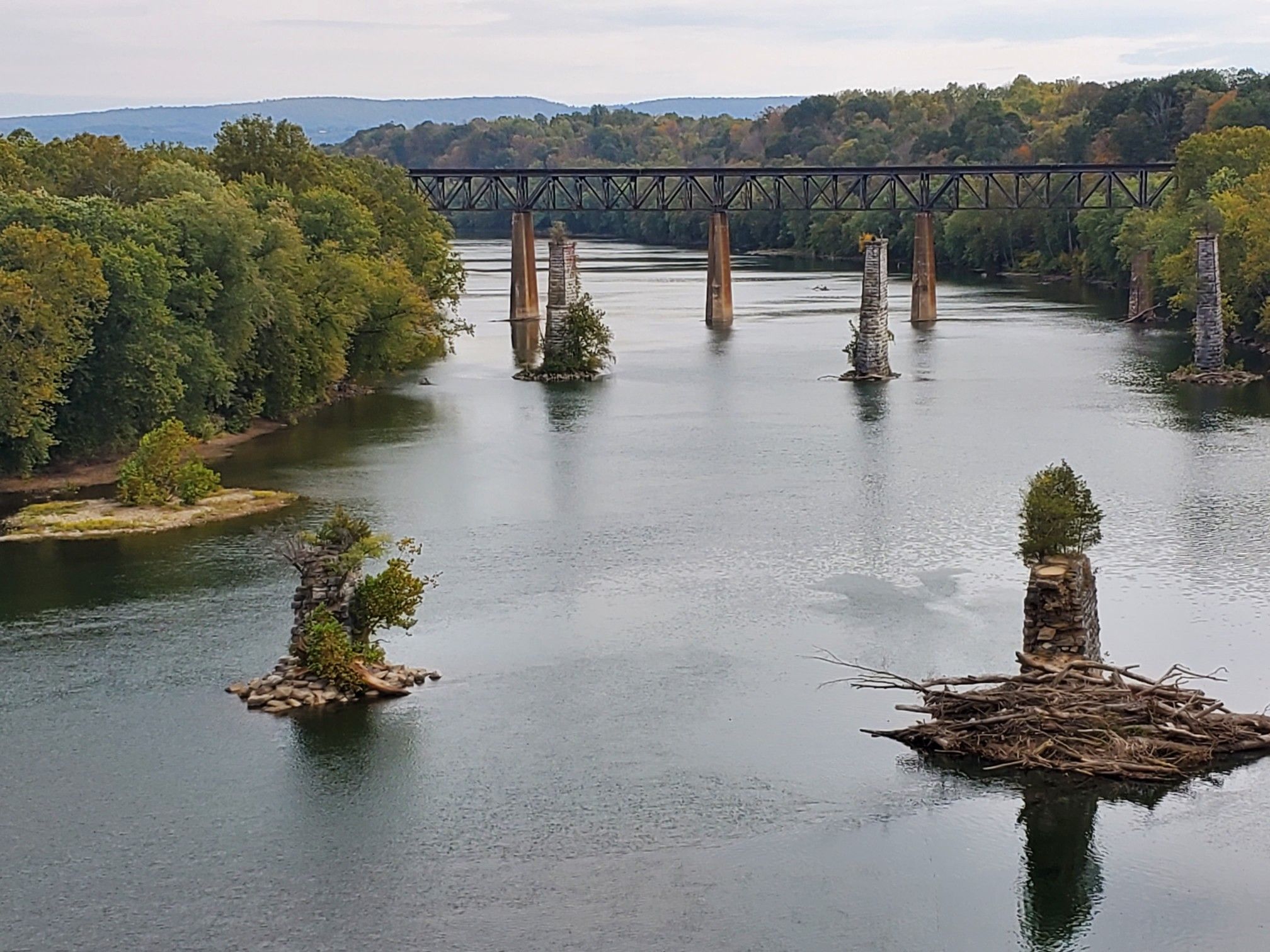 River with old bridge piers and a distant bridge under an overcast sky. - View of the Shenandoah River – Shenandoah Pulp Factory Ruins loop from Duffields