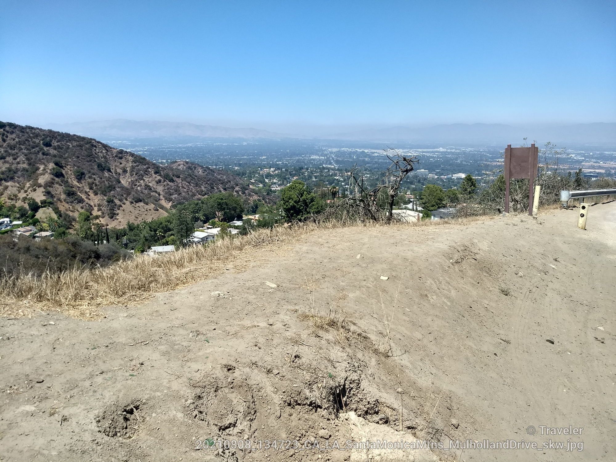 Dry dirt path overlooking a distant city and hazy mountains on a sunny day. - San Vicente Mountain Viewpoint – Mulholland Drive Gravel Path loop from Encino Reservoir