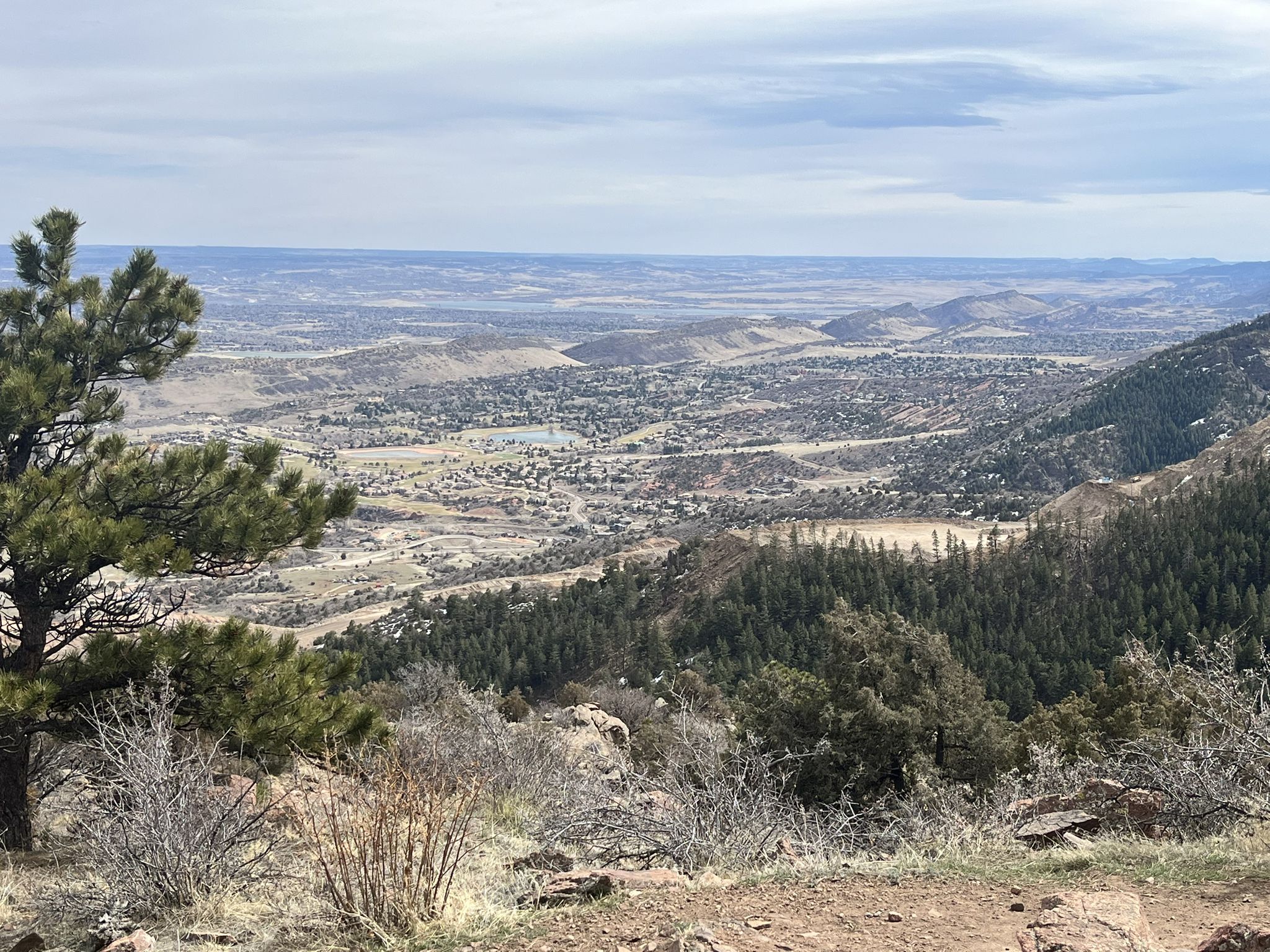 Expansive view of a valley with a town and forested hills under cloudy skies. - Turkey Trot Trail – Castle Trail loop from Morrison