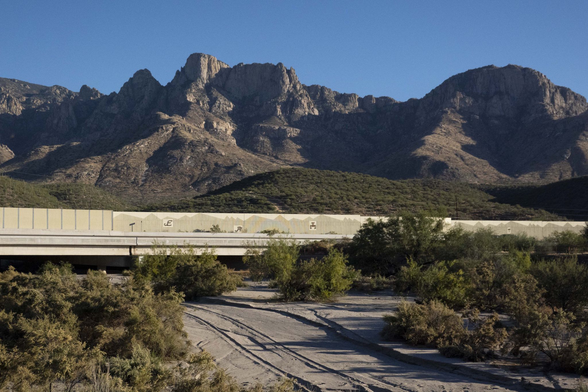 A highway overpass crosses a desert wash, with rugged mountains in background. - Cañada del Oro River Trail loop from In-N-Out Burger