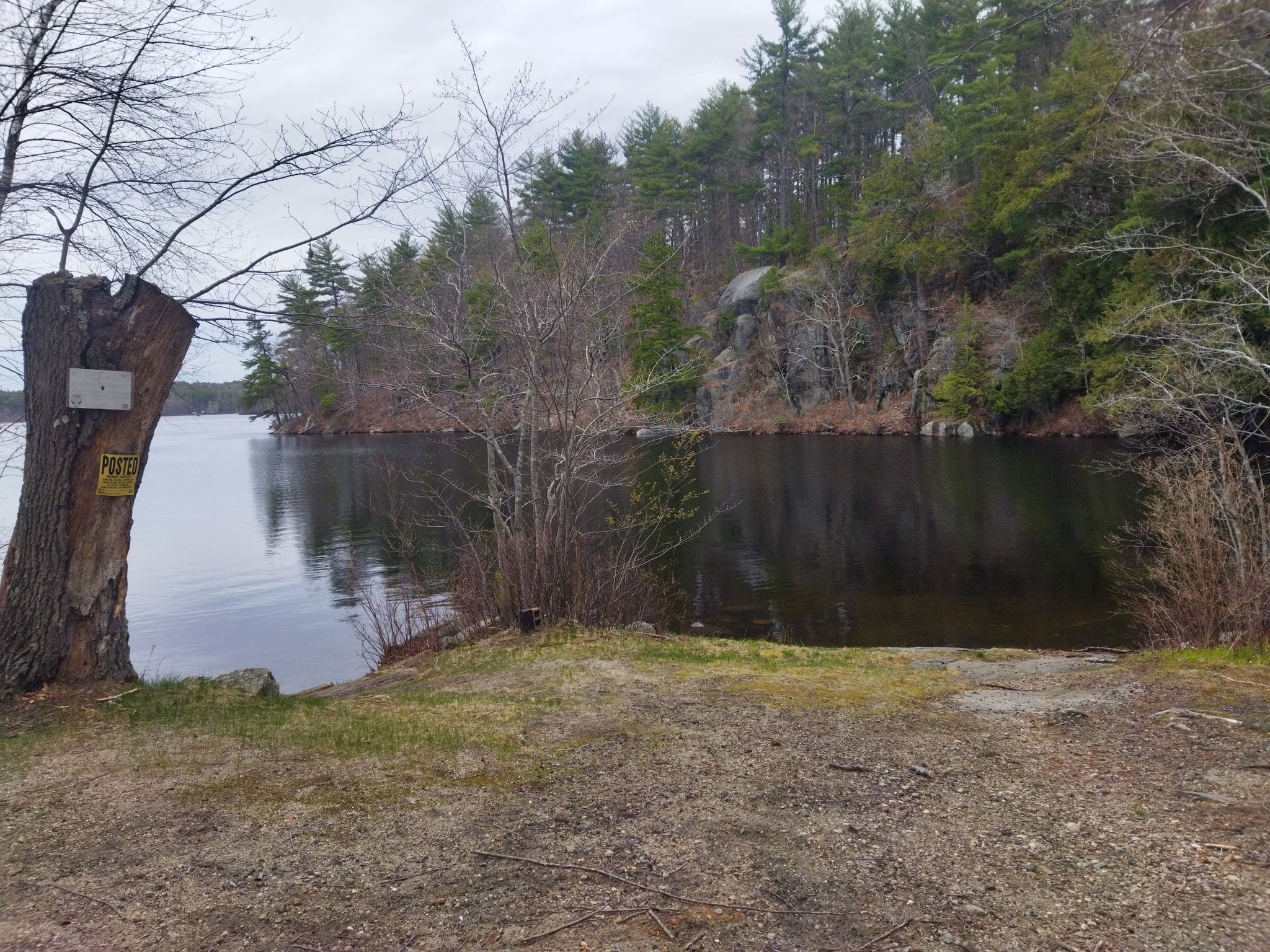A calm lake with a rocky, forested shore under an overcast sky. - Onway Lake – Onway Lake loop from Epping