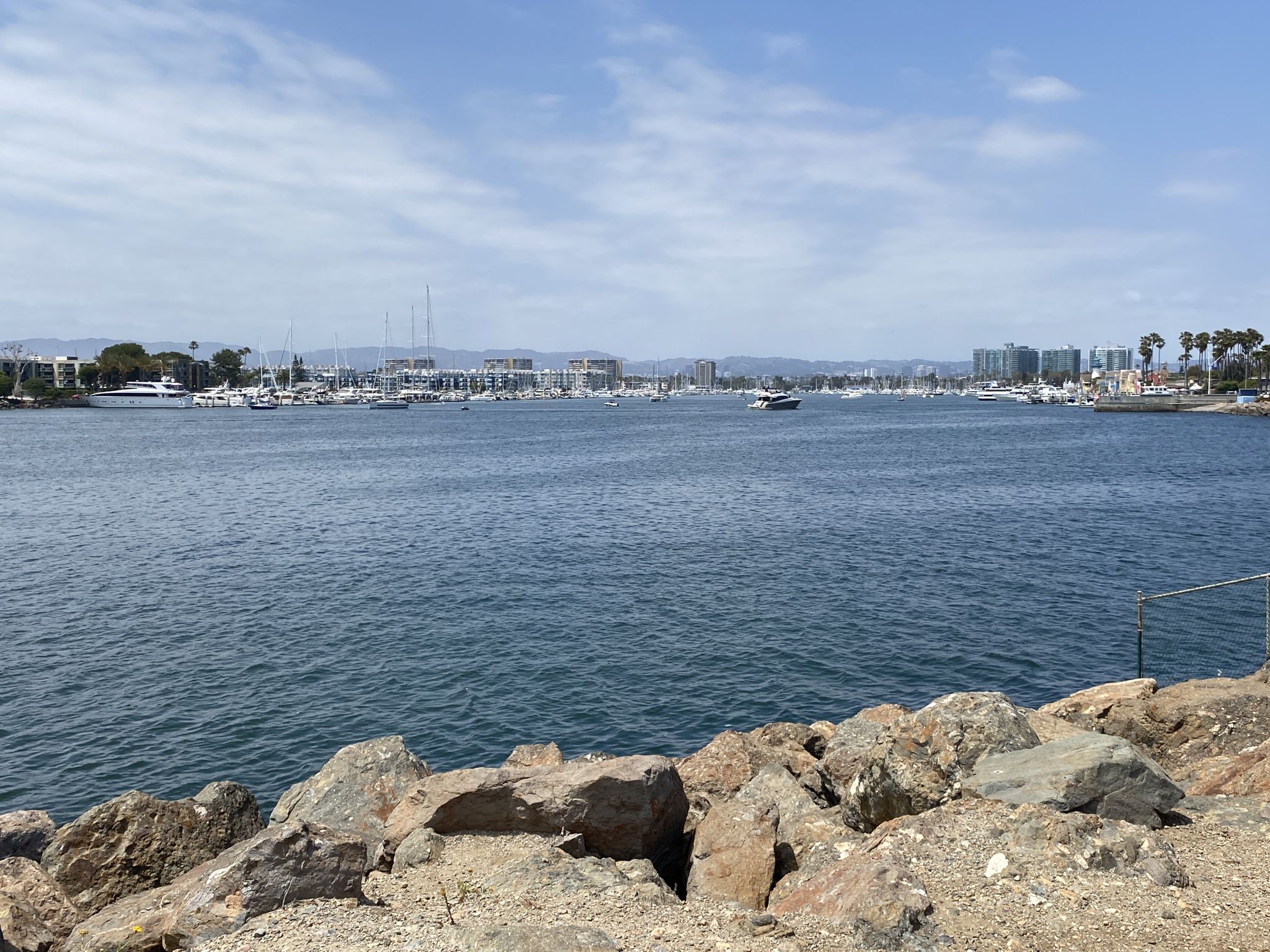 Wide marina with many boats, distant city, and rocky foreground. - Torrance Beach – El Segundo Beach loop from Lomita