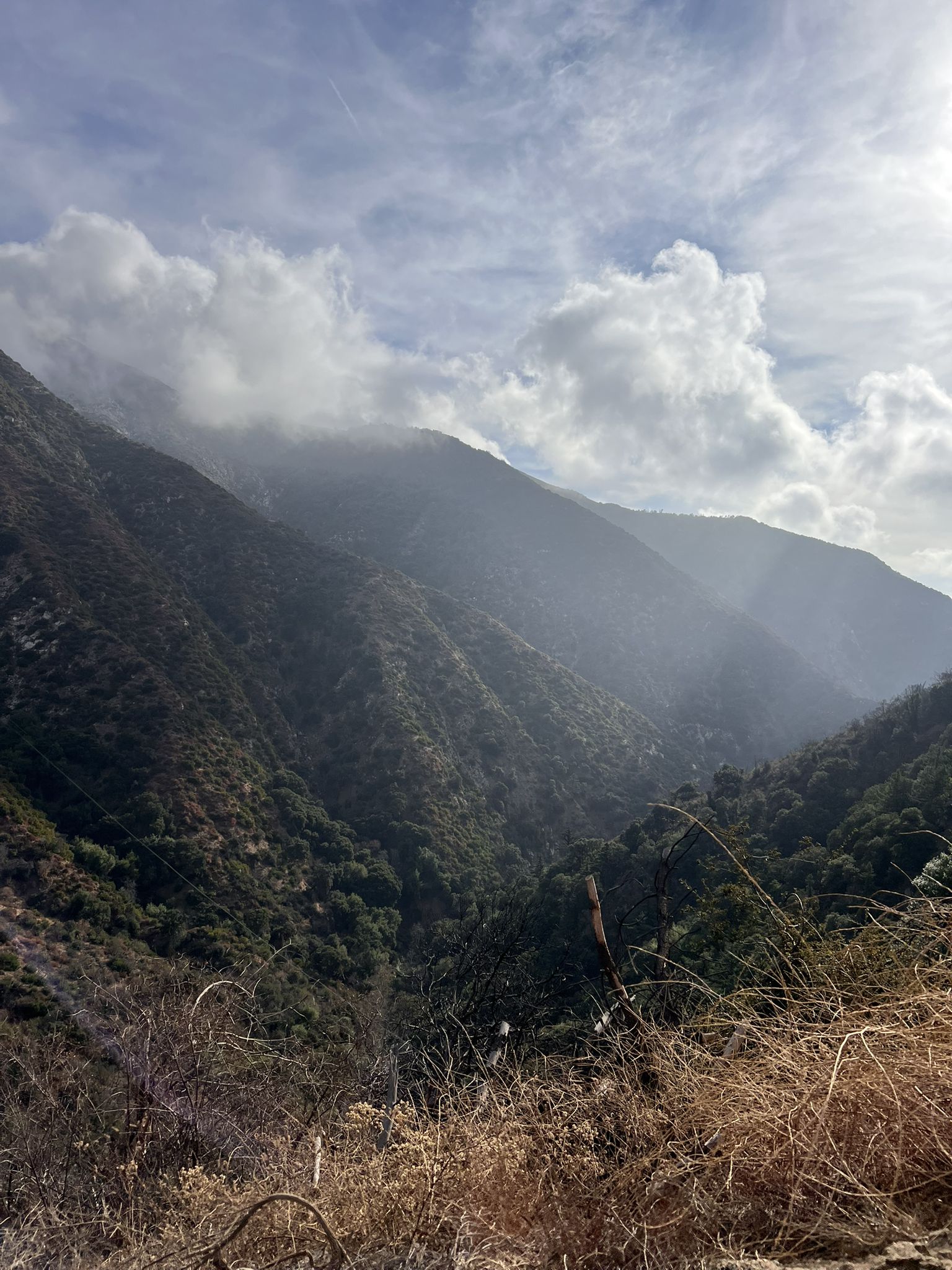 Cloud-covered mountains and valleys with sunlight breaking through, creating a dramatic scene. - Gabrielino Trail