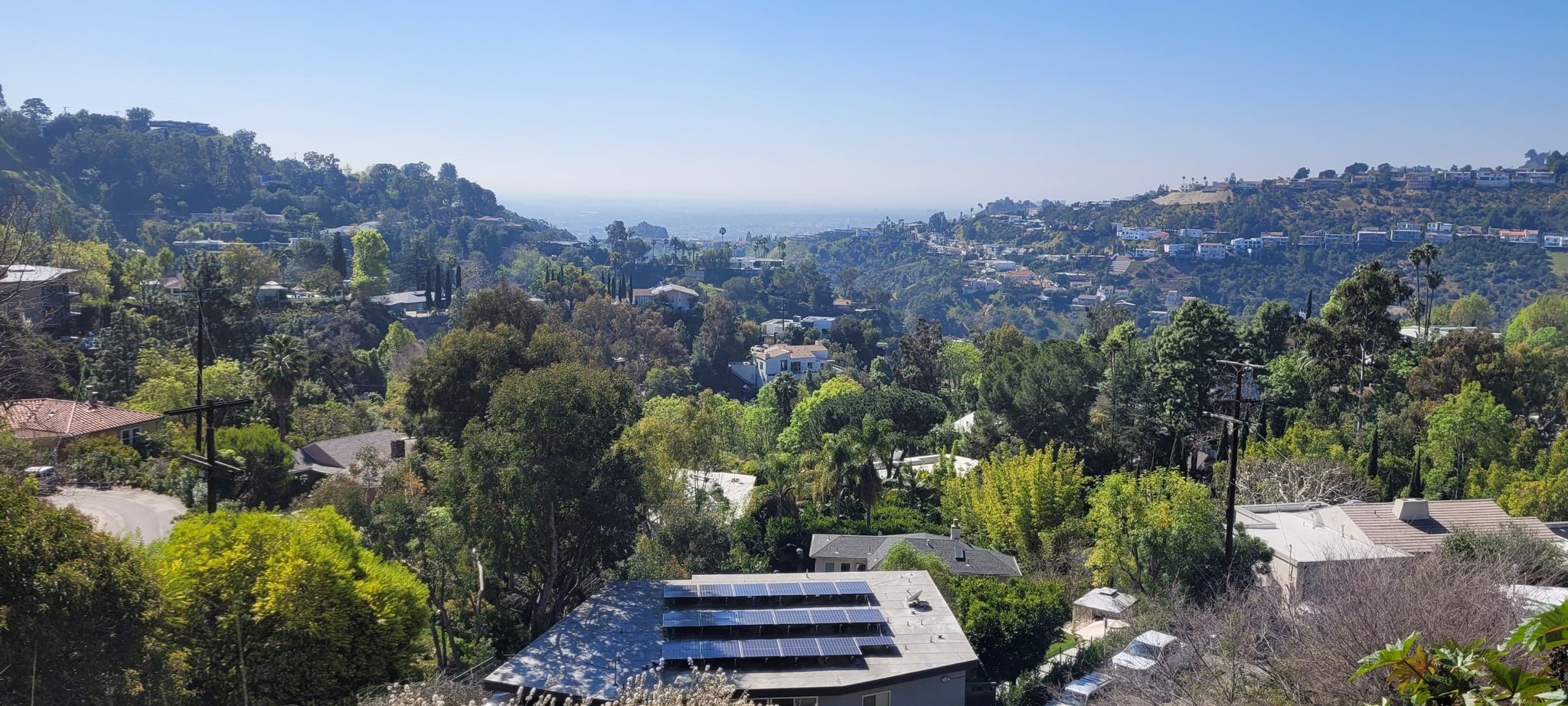Houses on green hillsides with solar panels, overlooking a distant ocean. - Chateau Marmont – Muholland Drive loop from West Hollywood