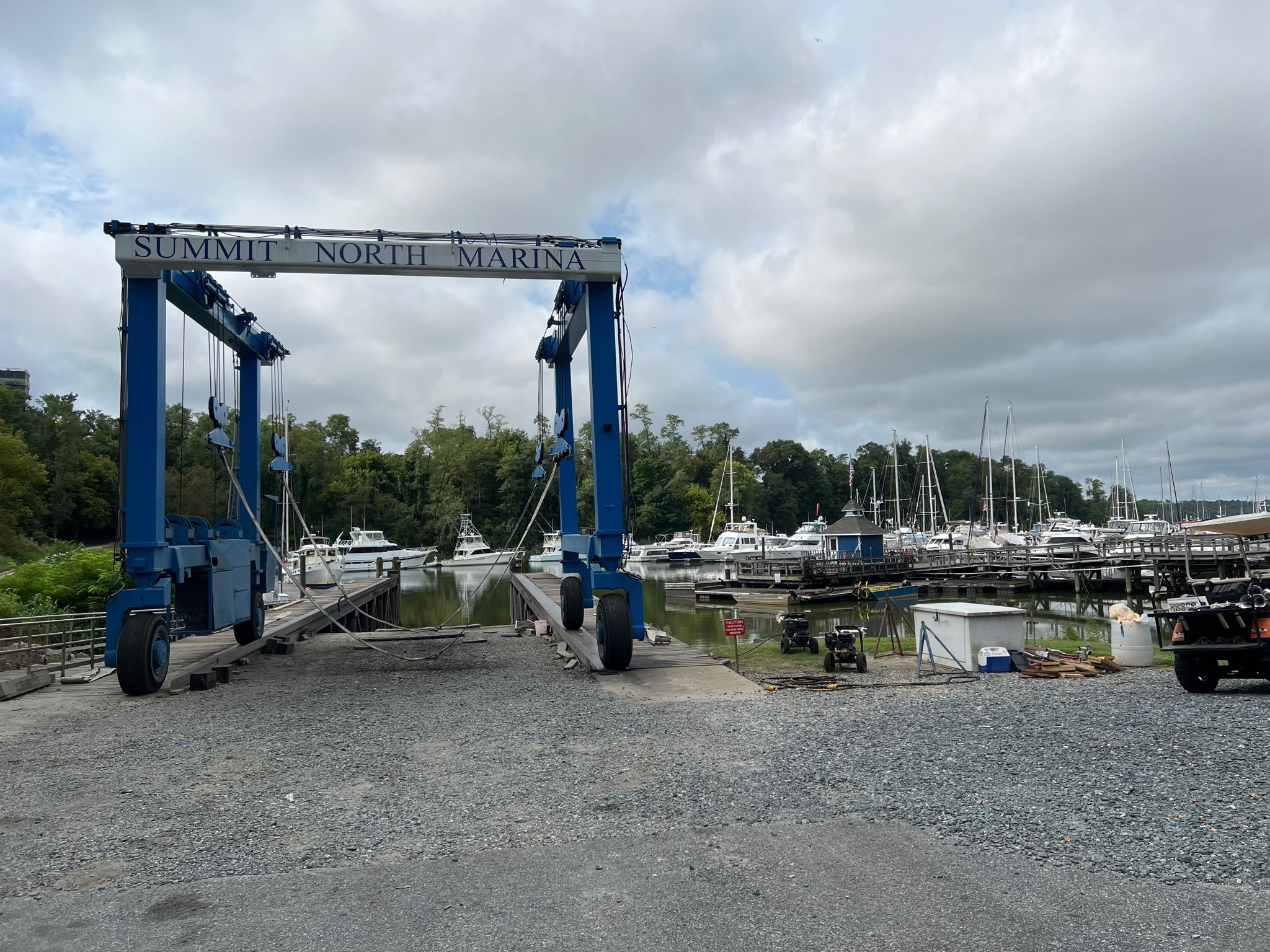 Large blue boat lift at a marina with boats under a cloudy sky. - Mike Castle Trail – Summit Pointe loop from Summit Bridge