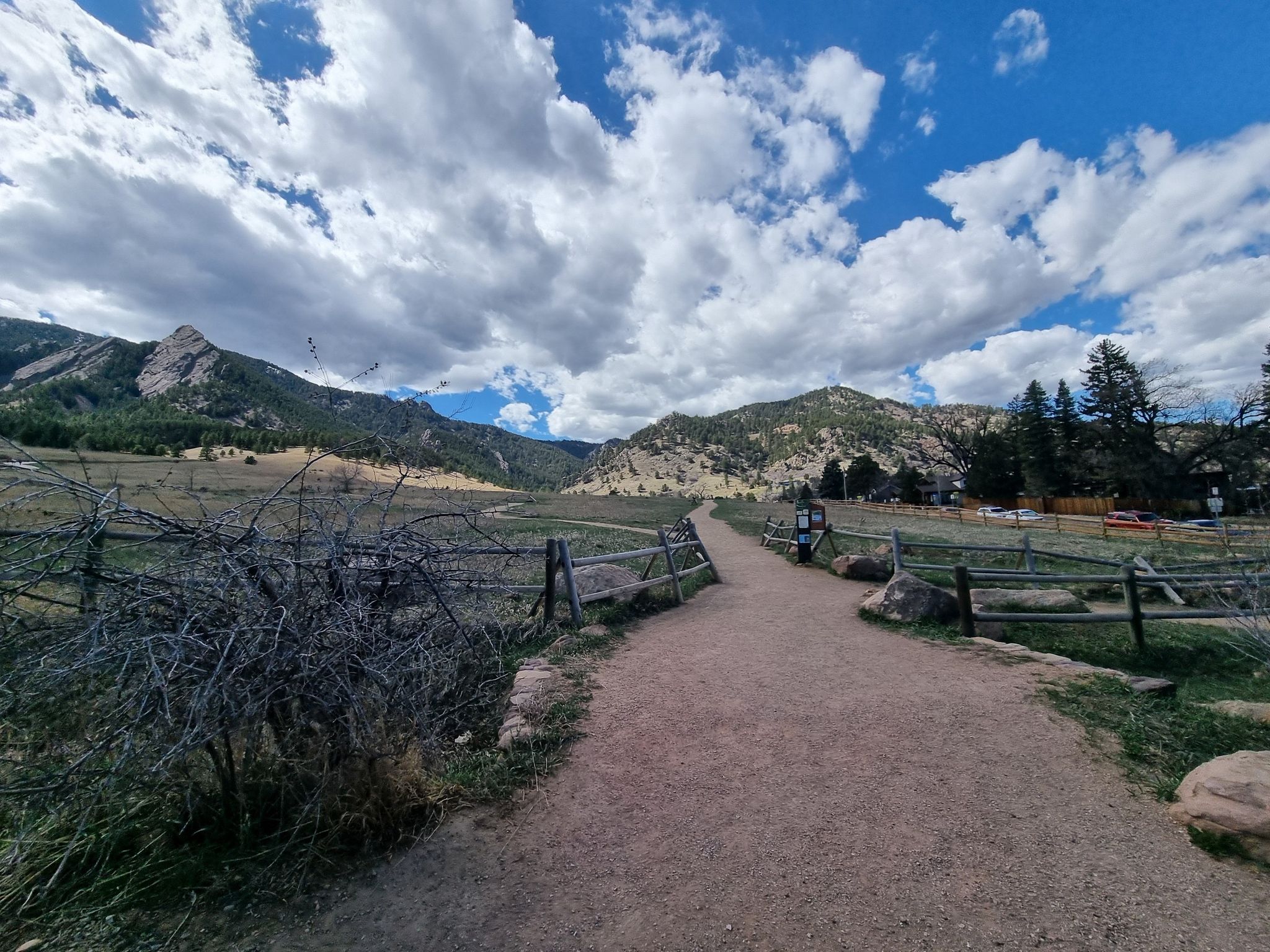 A dirt path leads through grassy fields towards distant mountains under a cloudy sky. - Flagstaff Road – Wonderland Lake loop from Foothills Community Park