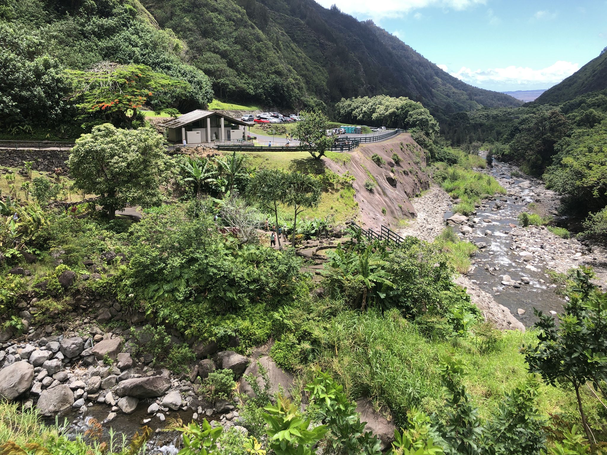 Lush green mountain valley with a river and a building under bright daylight. - ʻĪao Needle Lookout Trail and Ethnobotanical Loop