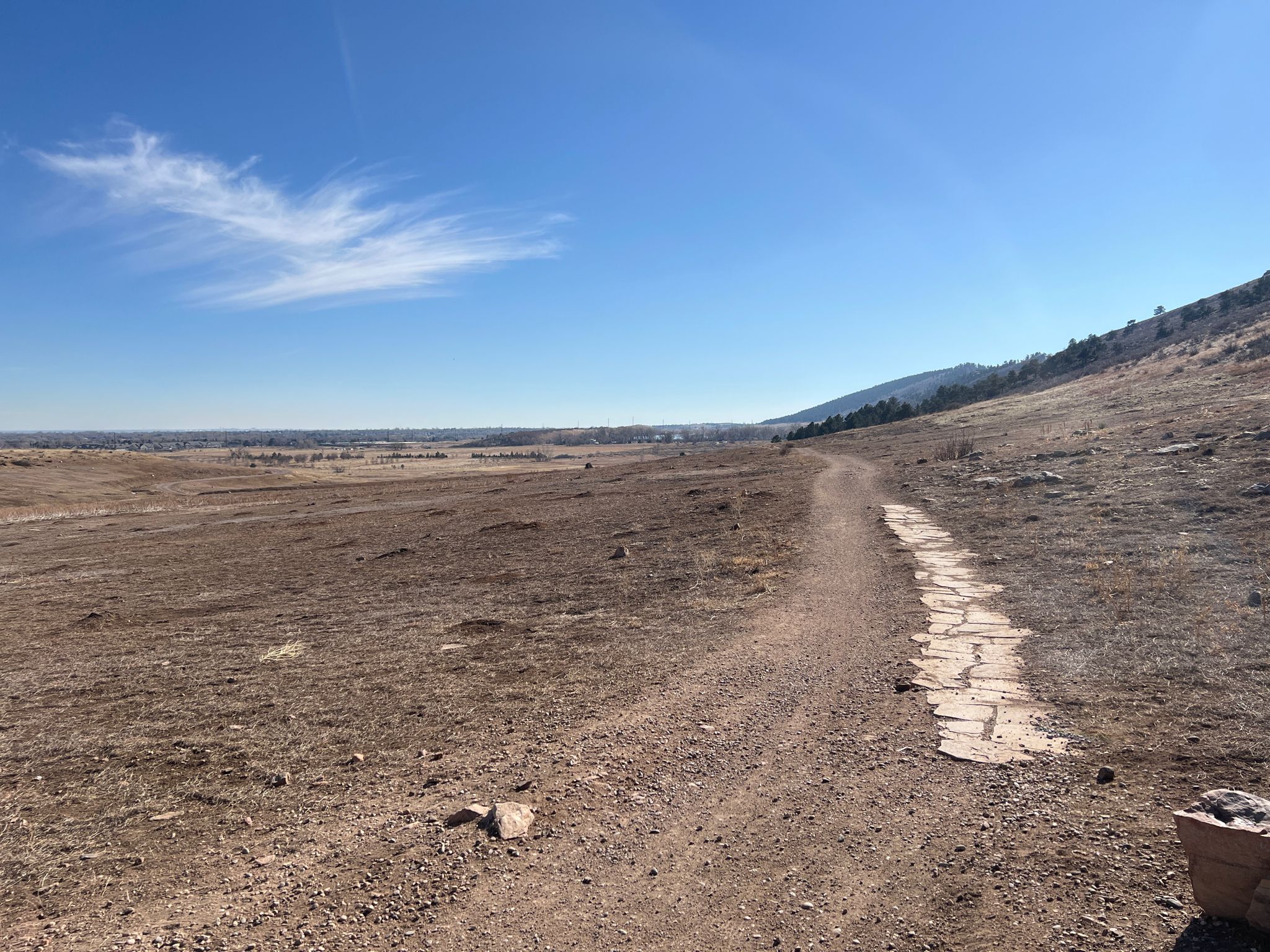 A dirt path winds through a dry, open landscape under a clear blue sky. - Sunrise Beach – Horsetooth Reservoir loop from Saddle Ridge Natural Area
