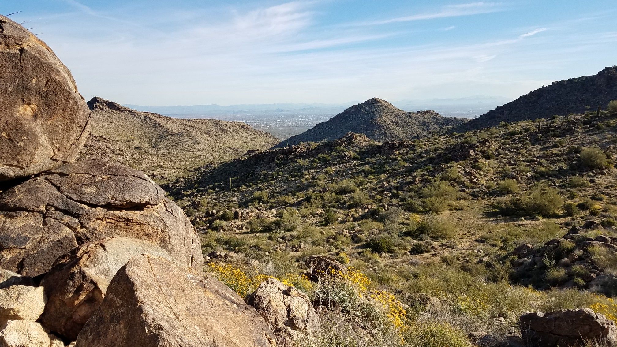 Rocky desert foreground, distant mountains, and valley under a bright sky. - Ford Canyon Loop Trail