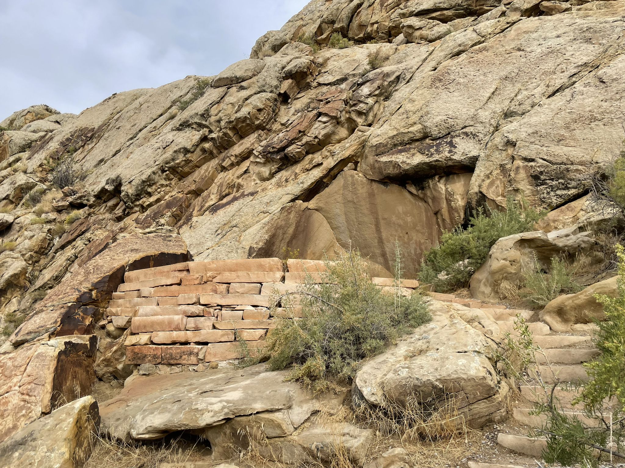 Rocky cliff face with a built stone wall and steps under an overcast sky. - Dinosaur National Monument Scenic Drive