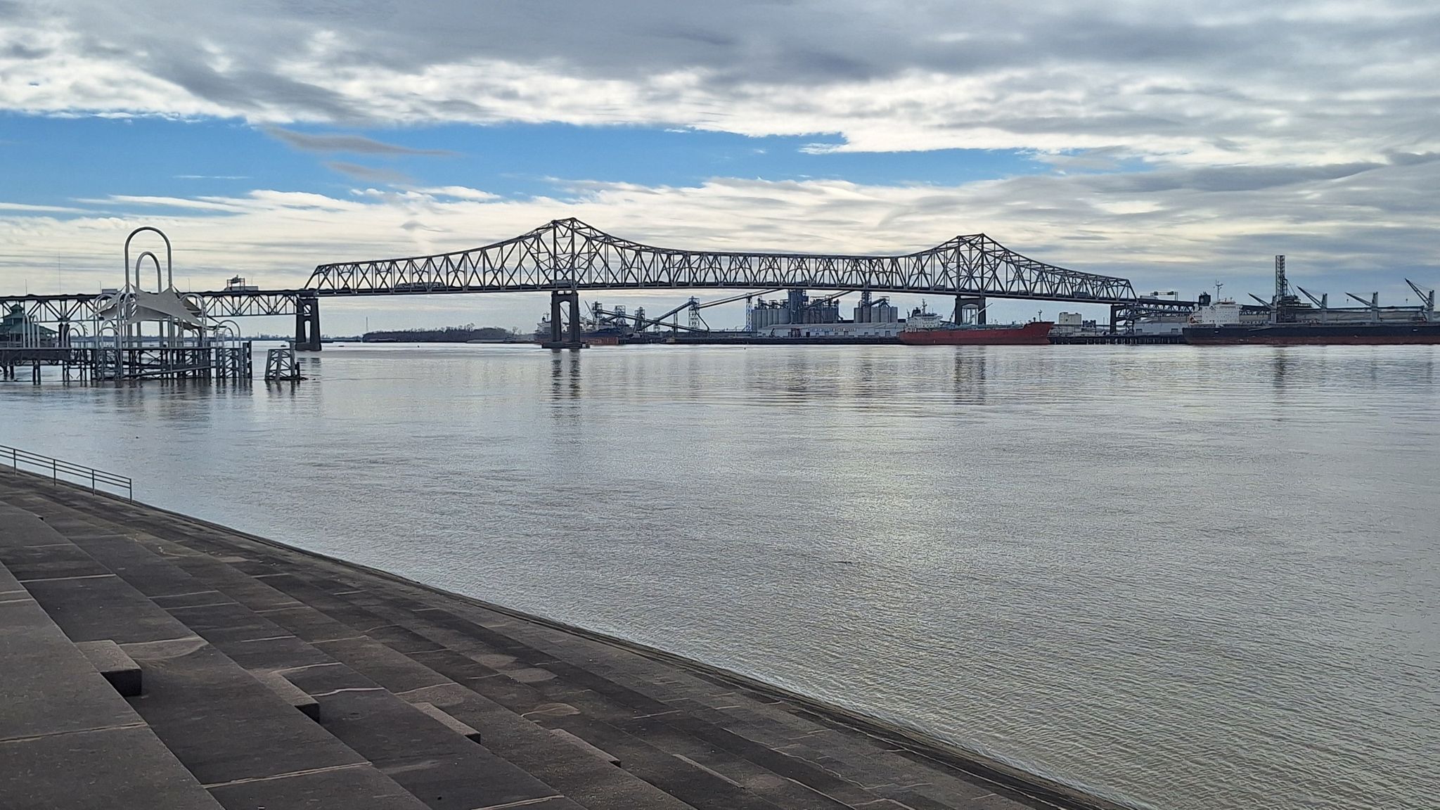 Large metal truss bridge spans a wide river under a partly cloudy sky. - Baton Rouge City Hall – Baton Rouge Waterfront loop from Baton Rouge