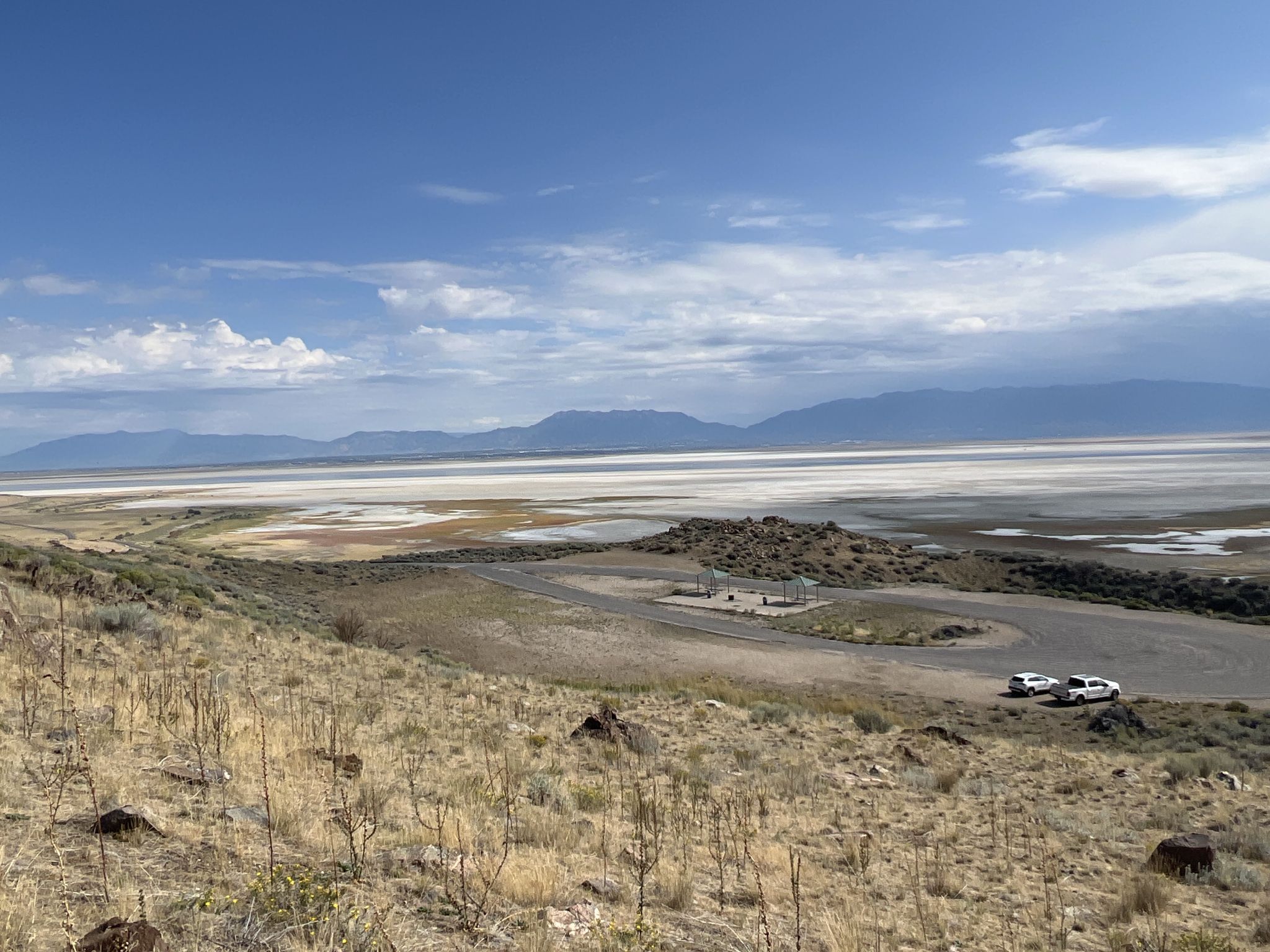 Panoramic view of a vast lakebed, distant mountains, and two cars. - Frary Peak Trail