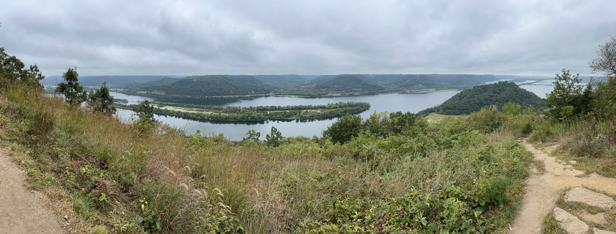 Panoramic view of a wide river winding through forested hills under a cloudy sky. - Brady's Bluff and Riverview Trail Loop