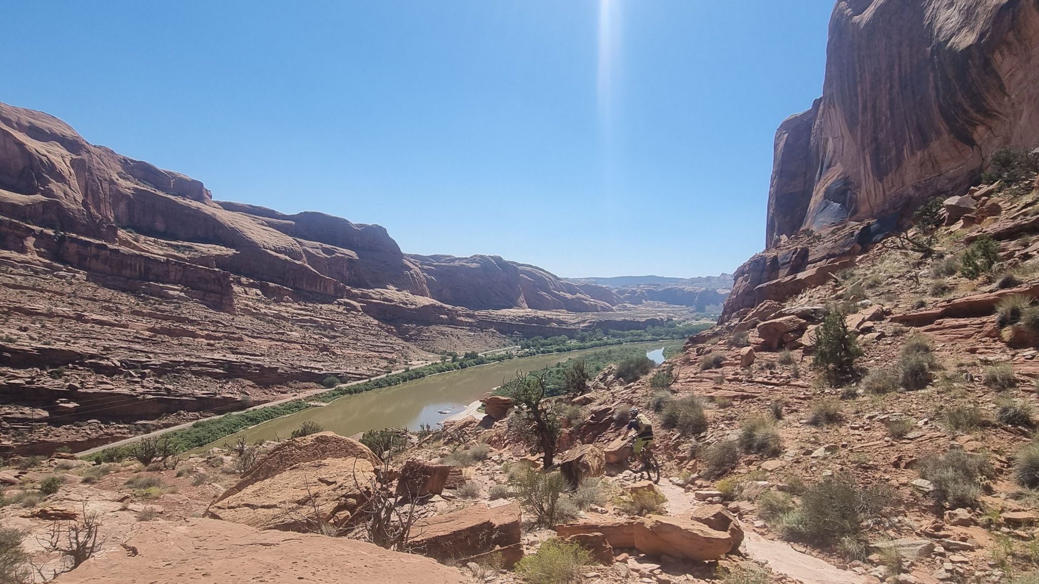 A green river flows through a deep red rock canyon under a bright blue sky. - Portal Overlook loop from Portal Trail