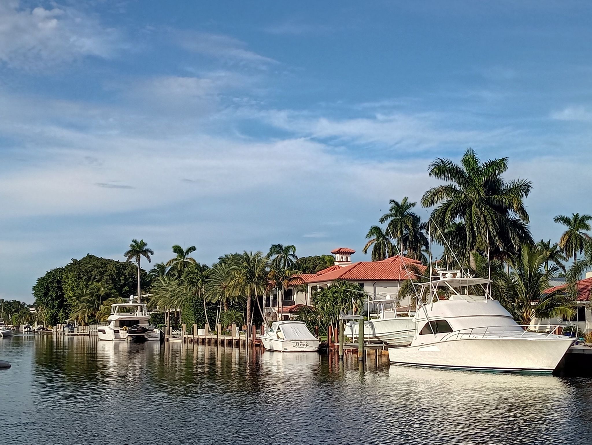 Boats docked by waterfront houses with palm trees under a blue sky. - East Coast Greenway: Fort Lauderdale Loop