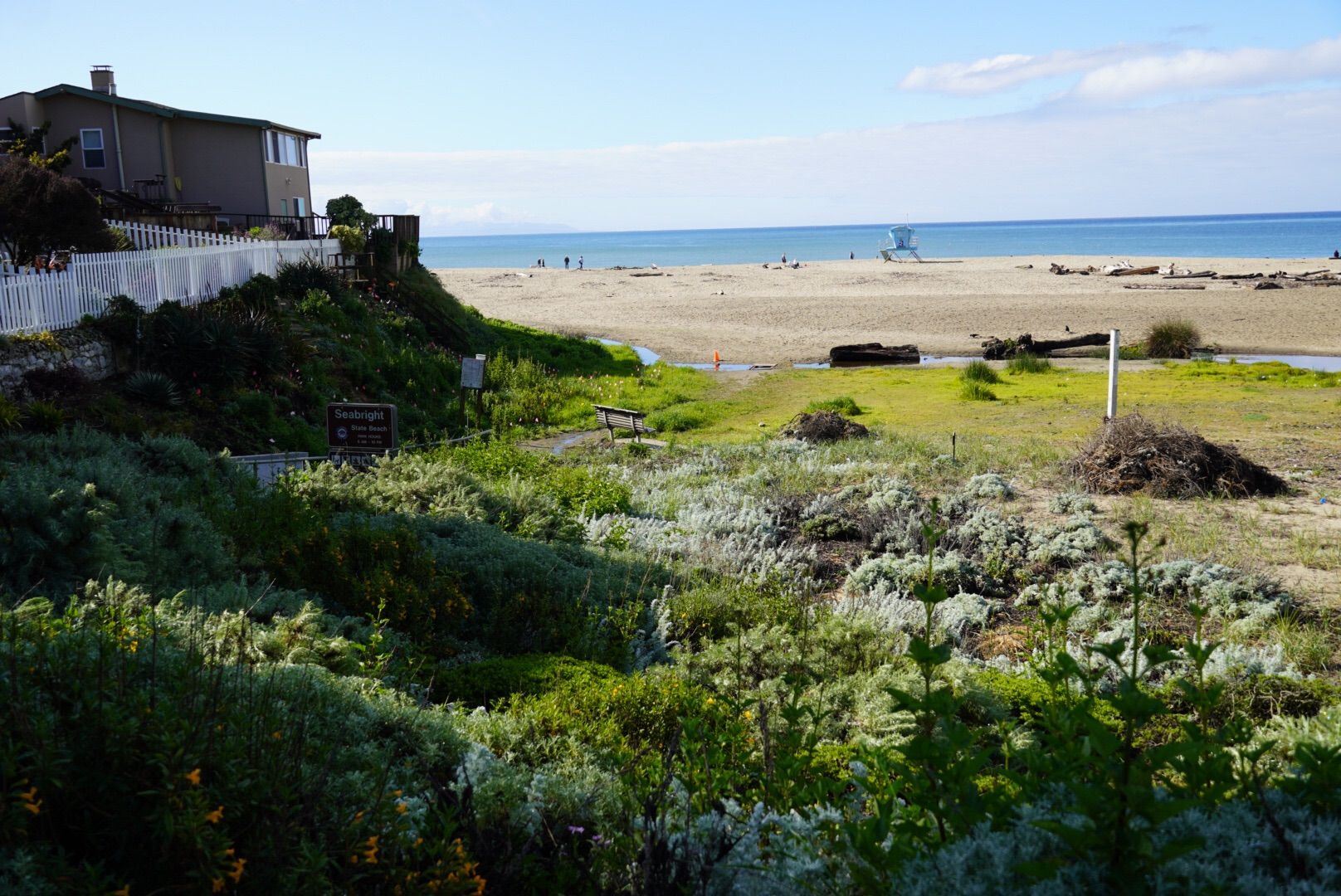 A house on a grassy bluff overlooks a sunny beach with distant ocean. - North Rodeo Gulch Road – Santa Cruz Boardwalk loop from Capitola