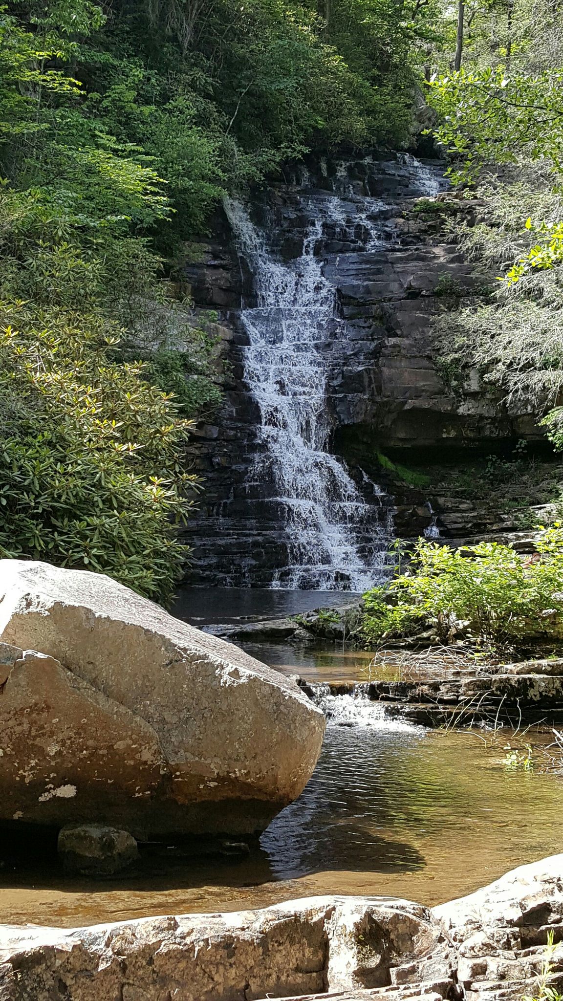 Waterfall cascades over rocky steps into a clear stream, surrounded by lush green trees. - Benton Falls – McKamy Lake Beach loop from Clemmer Trailhead parking area