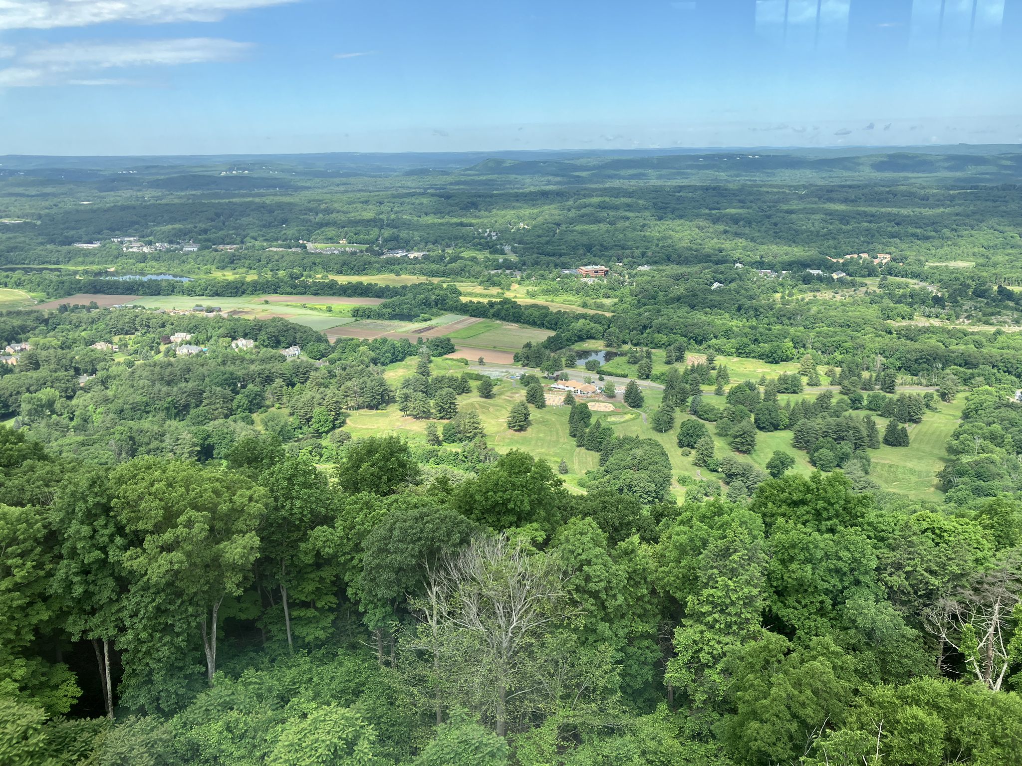 Aerial view of a vast green forested landscape under a blue sky. - Talcott Mountain Yellow Trail