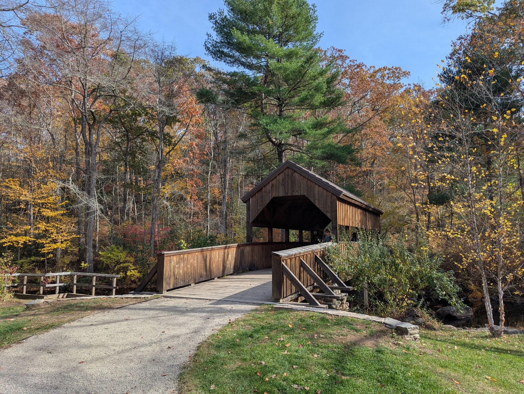 Wooden covered bridge on a sunny autumn day with colorful trees. - Vista Trail and Devil's Oven Loop