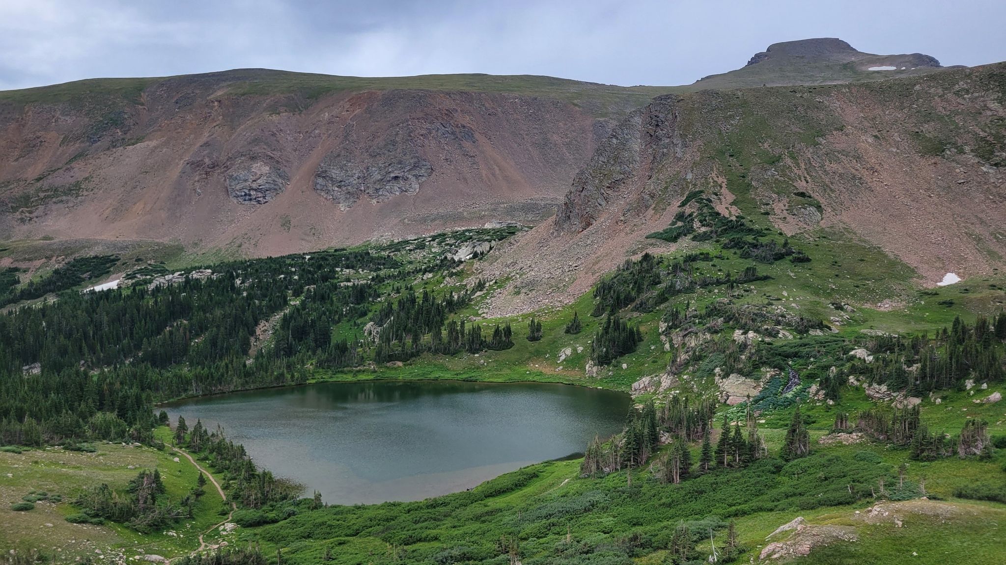 Dark alpine lake nestled among rocky, forested mountains under an overcast sky. - South Boulder Creek, Boulder Wagon, Rollins Pass and Forest Lakes Loop