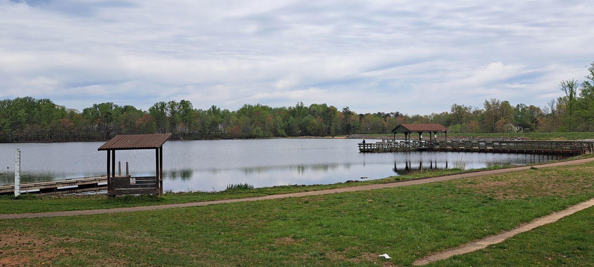 Lake with two covered docks and a grassy shore under a cloudy sky. - Lake Brittle loop