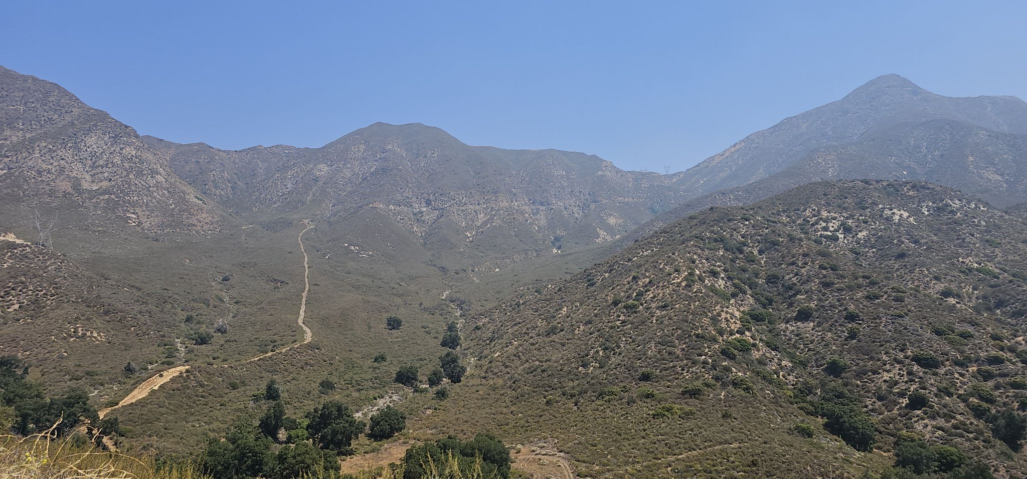 A vast mountain range covered in scrub, with a winding dirt road. - Little Tujunga Canyon Loop