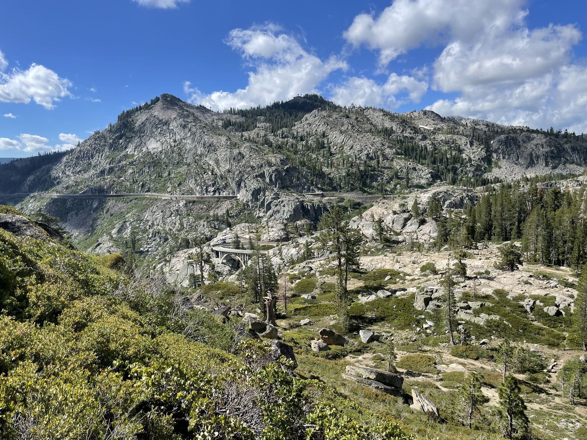 Rocky mountains with a winding road under a bright, cloudy sky. - George R. Stewart Peak via Pacific Crest Trail