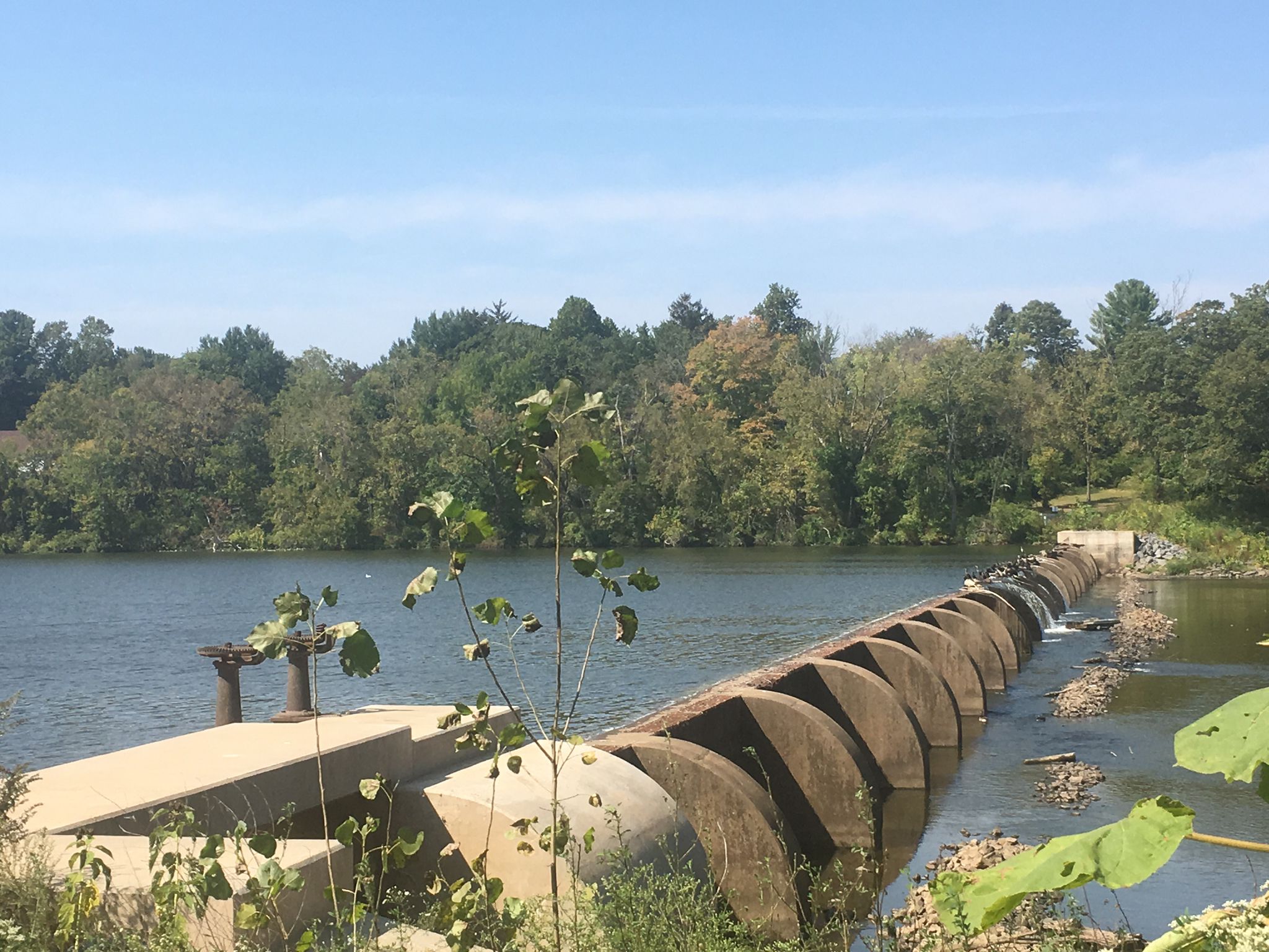 A large concrete dam spans a wide river under a clear sky. - Delaware and Raritan Canal Trail Loop