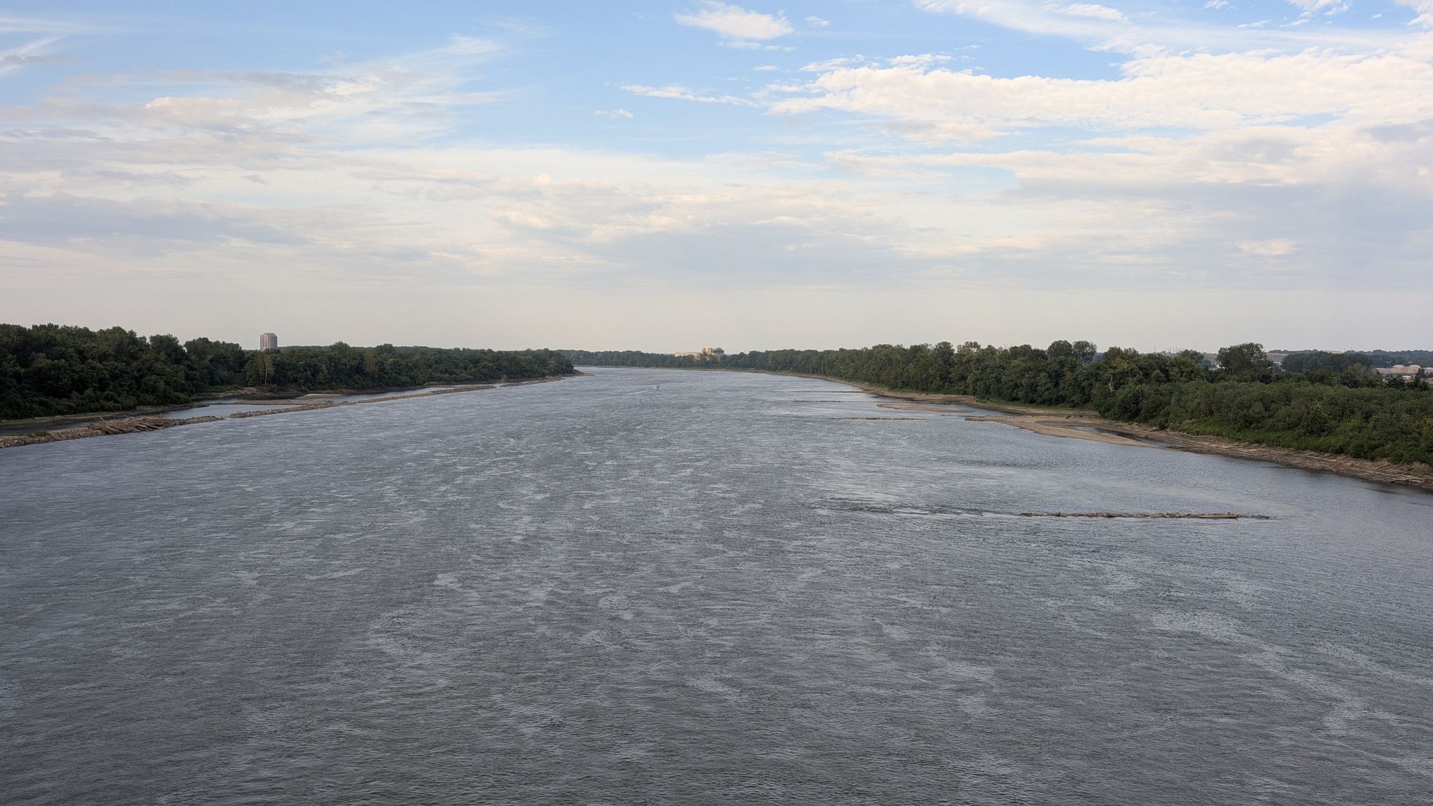 Wide river flowing between lush green forested banks under a cloudy sky. - Katy Trail and Creve Coeur Lake Loop