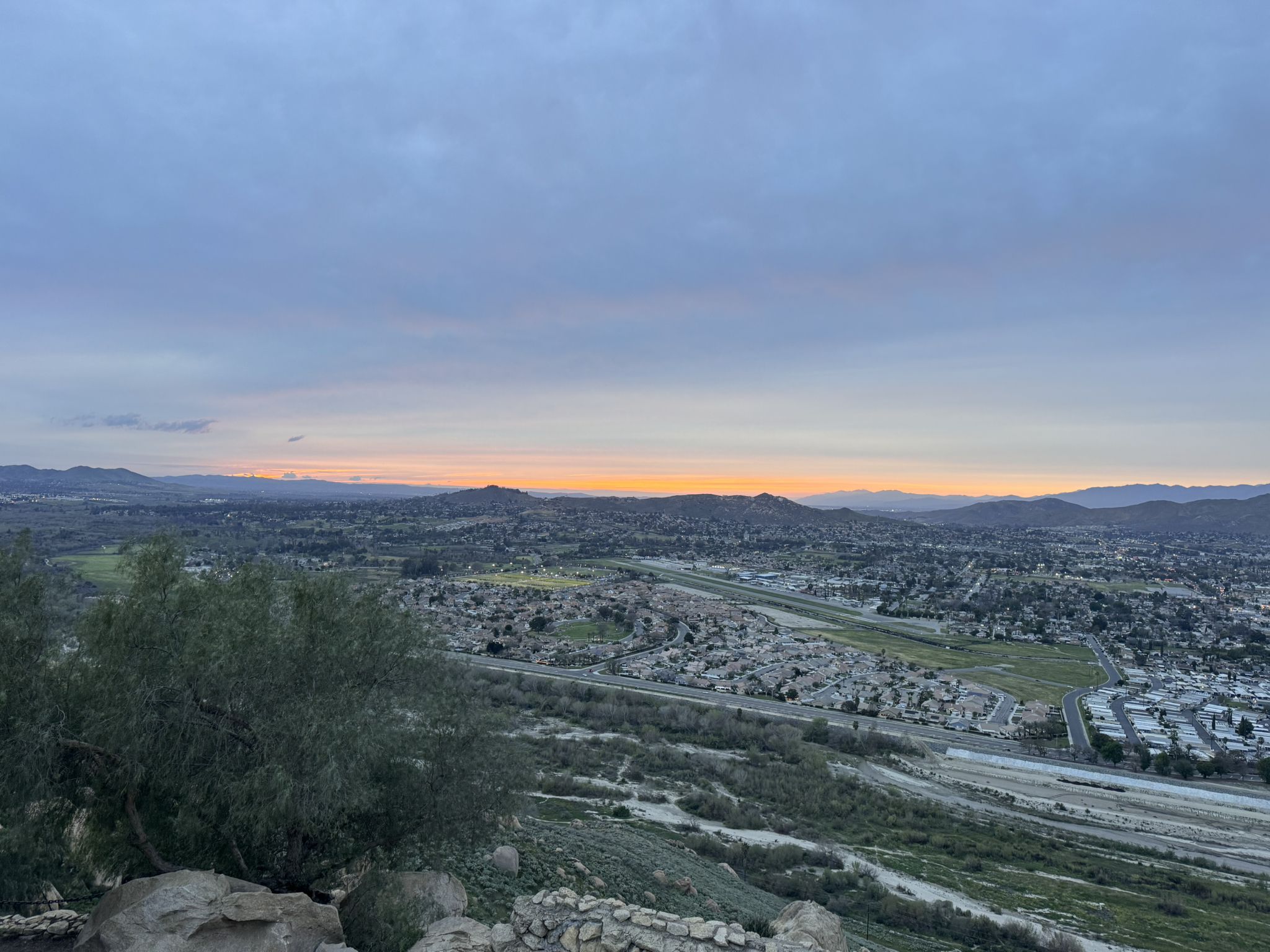 Panoramic view of a town and mountains at dusk under a cloudy sky. - Mount Rubidoux Trail