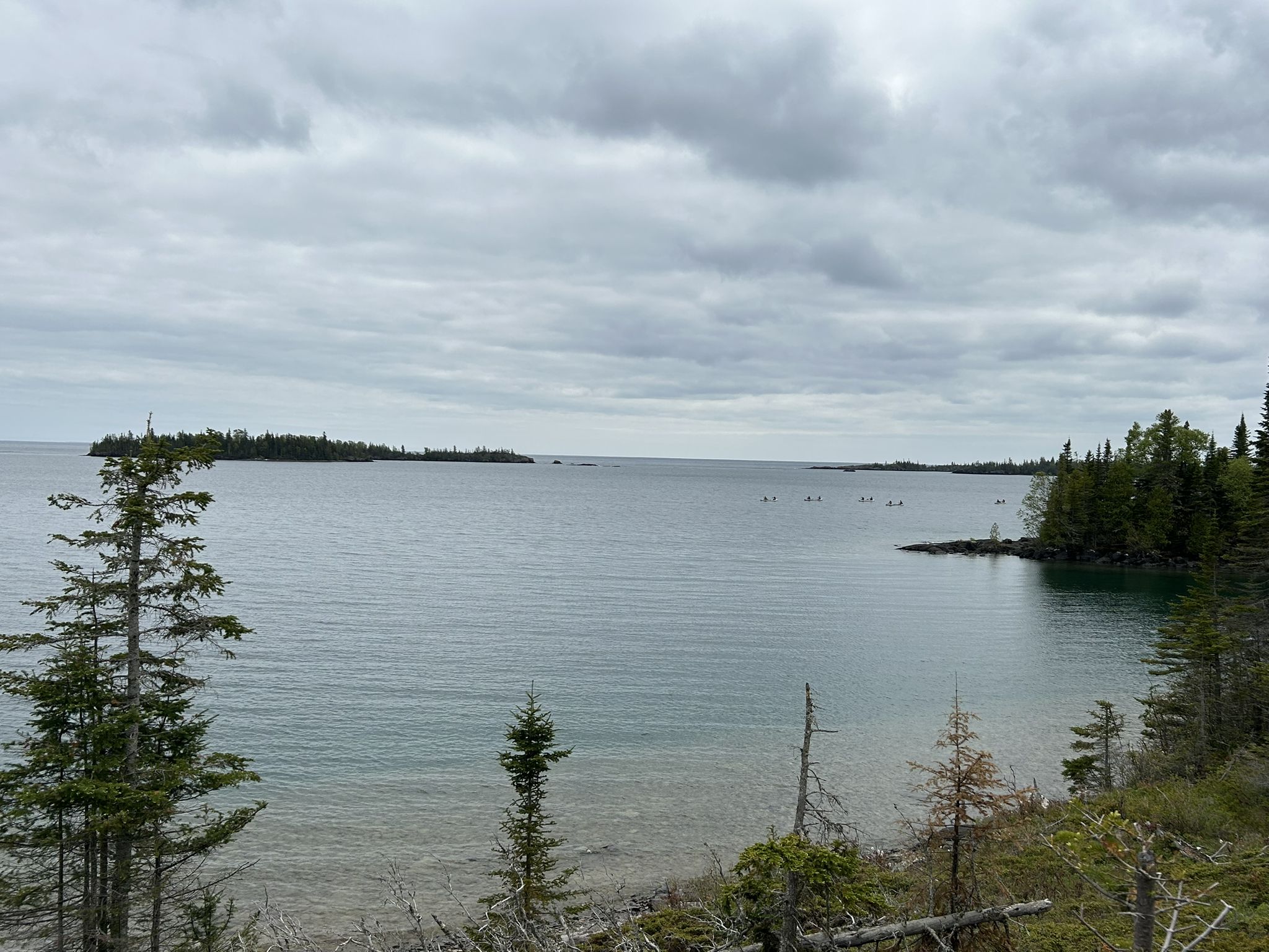 Wide view of a large lake with islands and evergreen trees under a cloudy sky. - Rock Harbor Trail