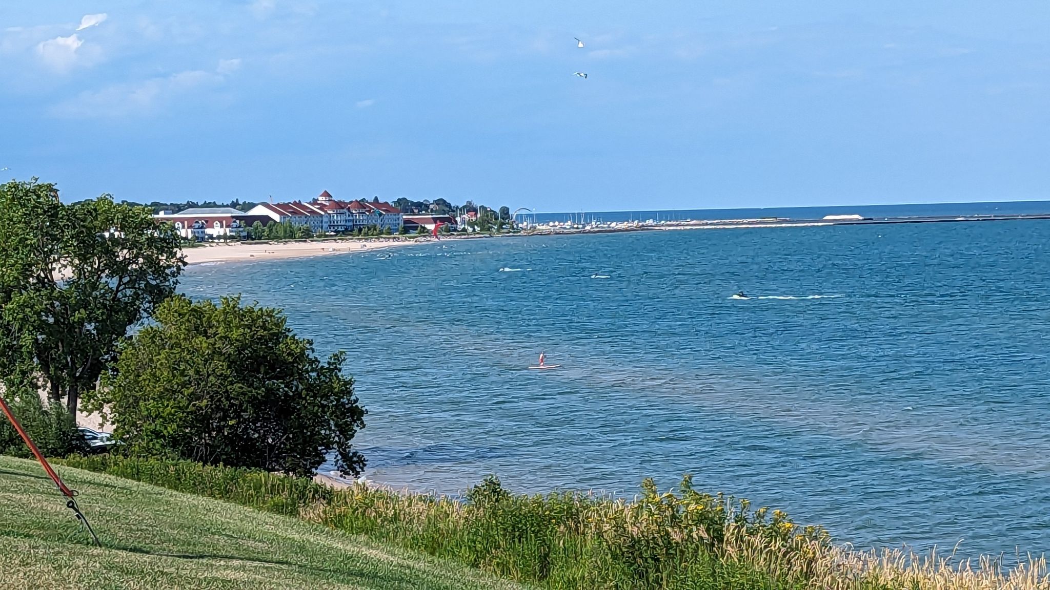 Expansive blue water with a distant beach, buildings, and trees under a bright sky. - From Port Washington to Sheboygan - LMCT (Lake Michigan Circle Tour)