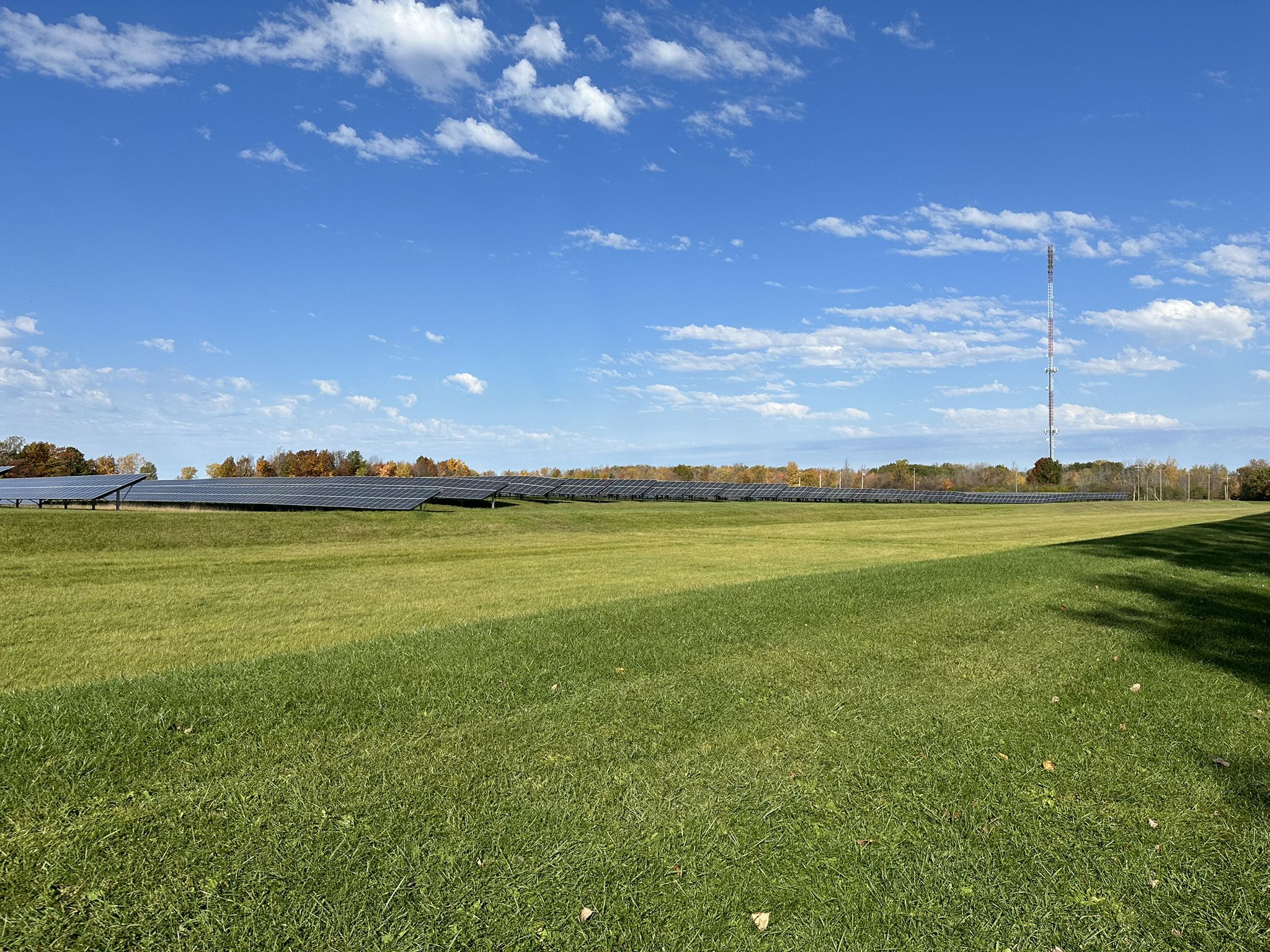 Solar panels in a green field under a bright blue sky. - Erie Canalway and Tonawanda Rails-to-Trails Loop