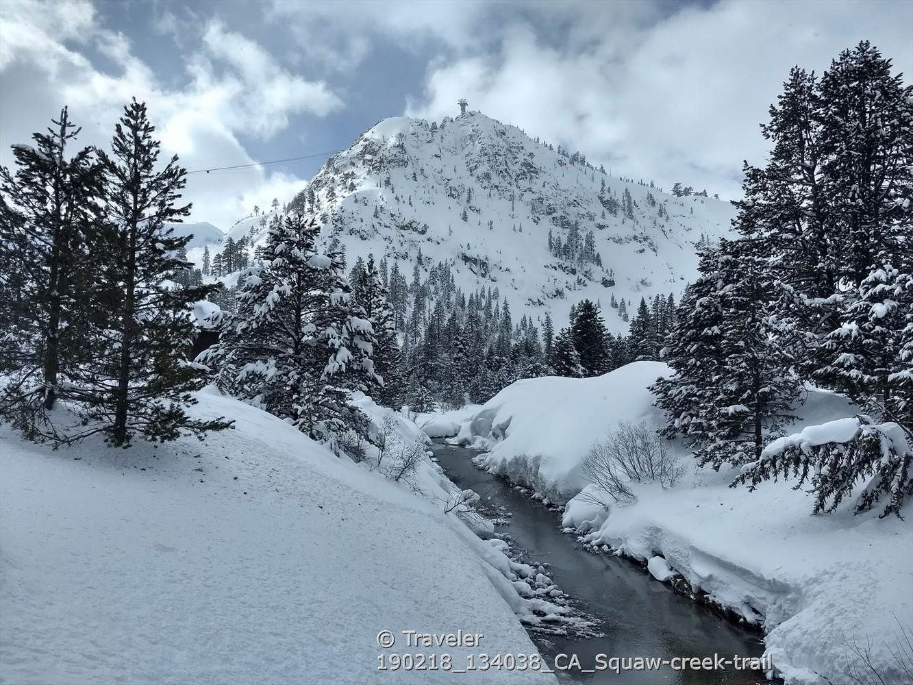 Snowy mountain peak overlooking a partially frozen stream. - The Village at Palisades Tahoe loop from Olympic Meadow Preserve