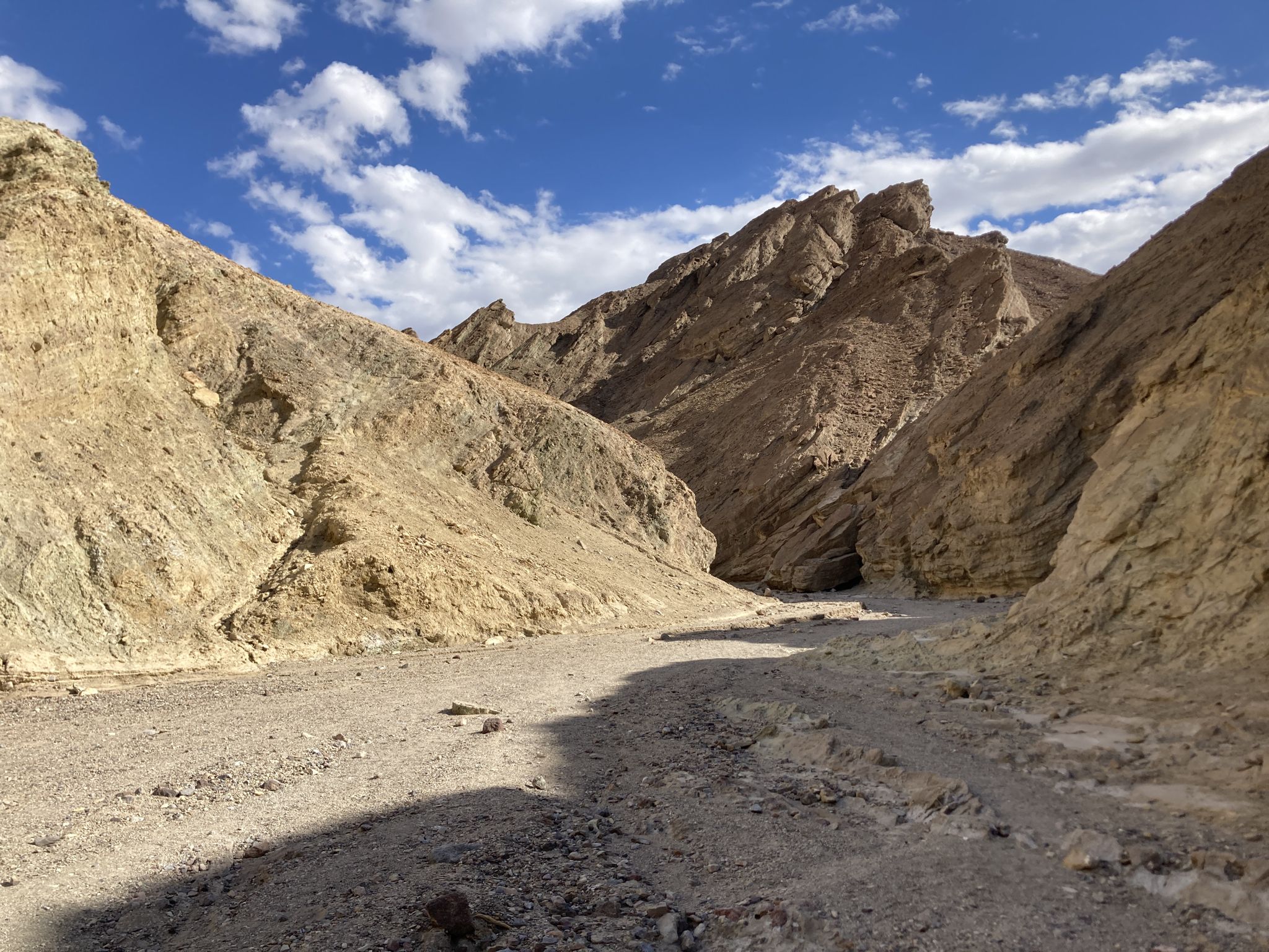 Rocky desert wash winding between steep, light-colored canyon walls under blue sky. - Golden Canyon Trail