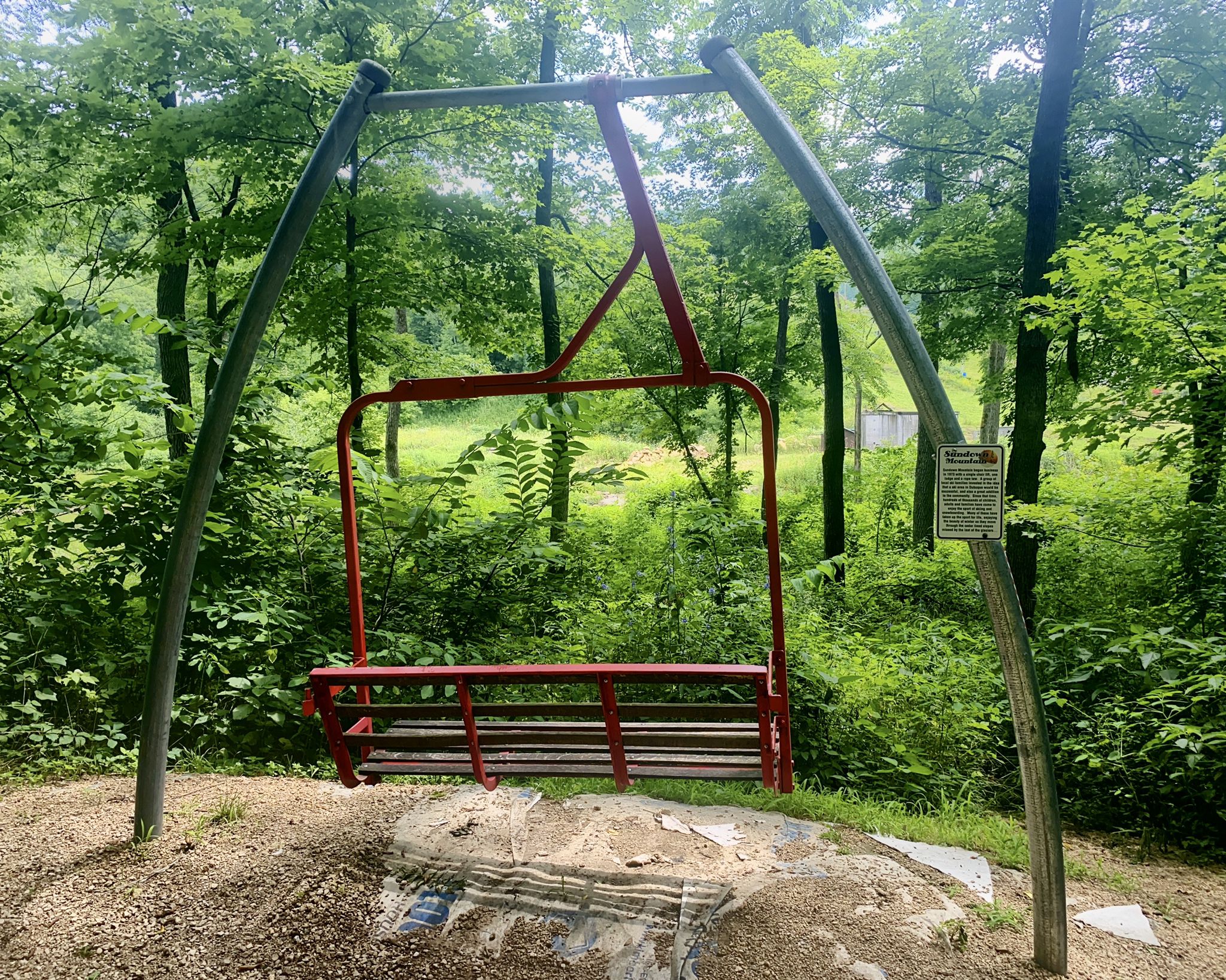 A red ski lift chair stands in a dense, green forest. - MIller-McGrath Wildlife Area loop from Durango