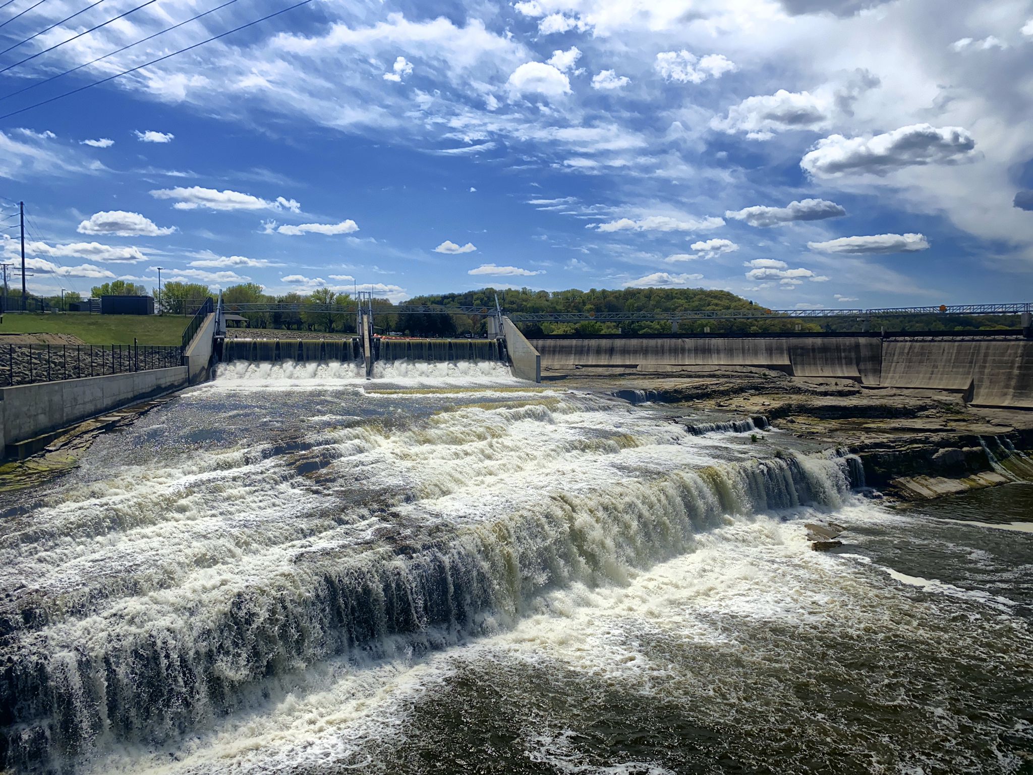 Wide view of a dam with powerful waterfalls under a blue sky. - Lake Byllesby – Lake Byllesby Dam loop from Randolph Township