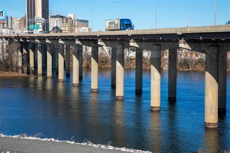 A long concrete bridge with traffic crosses a wide river under clear skies. - James River Canal Walk